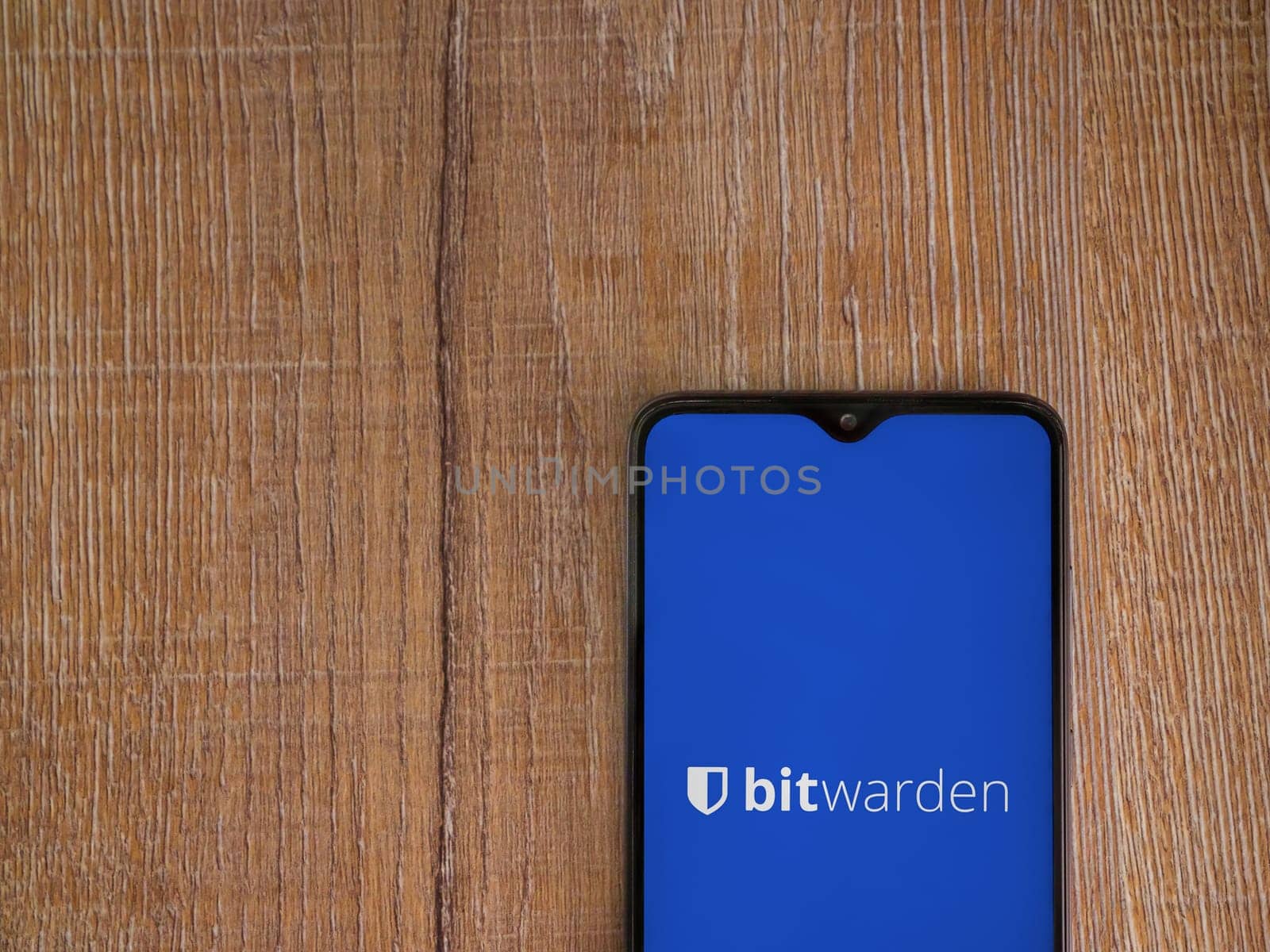 Lod, Israel - July 16,2023: Bitwarden Password Manager app launch screen on smartphone on wooden background. Top view flat lay with copy space.