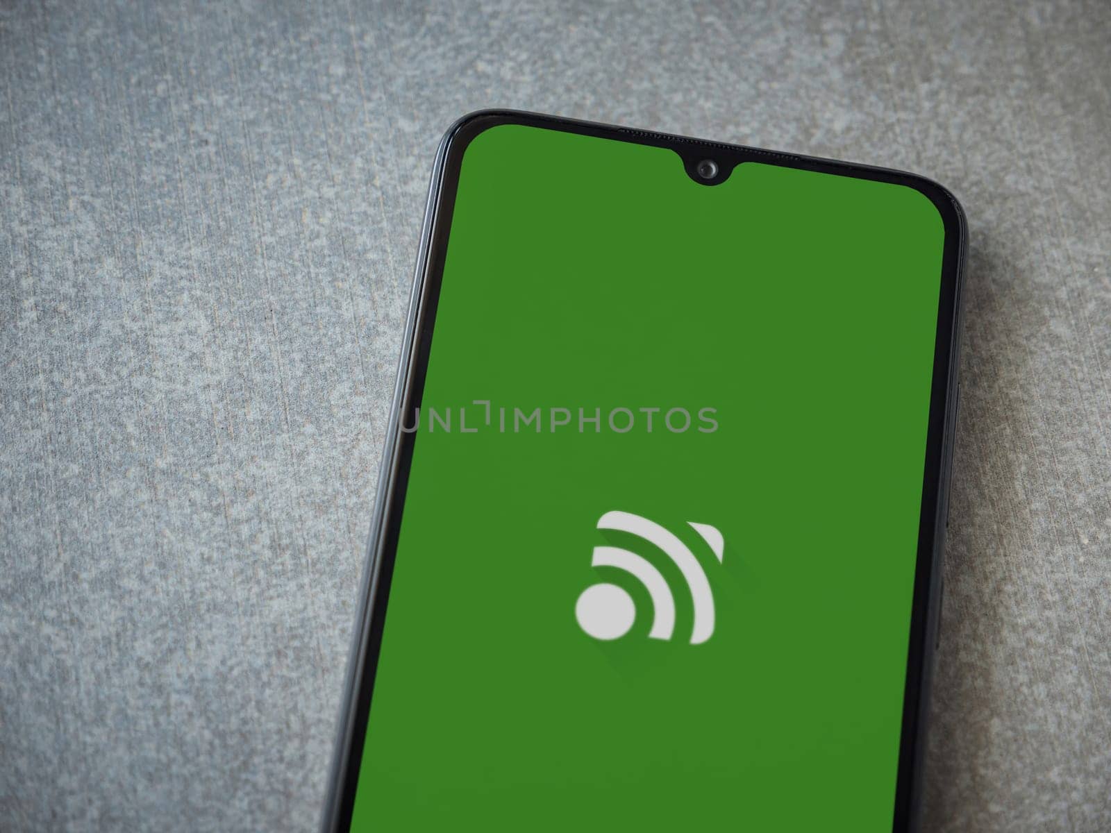 Lod, Israel - July 16,2023: Unified Remote app launch screen on smartphone on ceramic stone background. Top view flat lay with copy space.