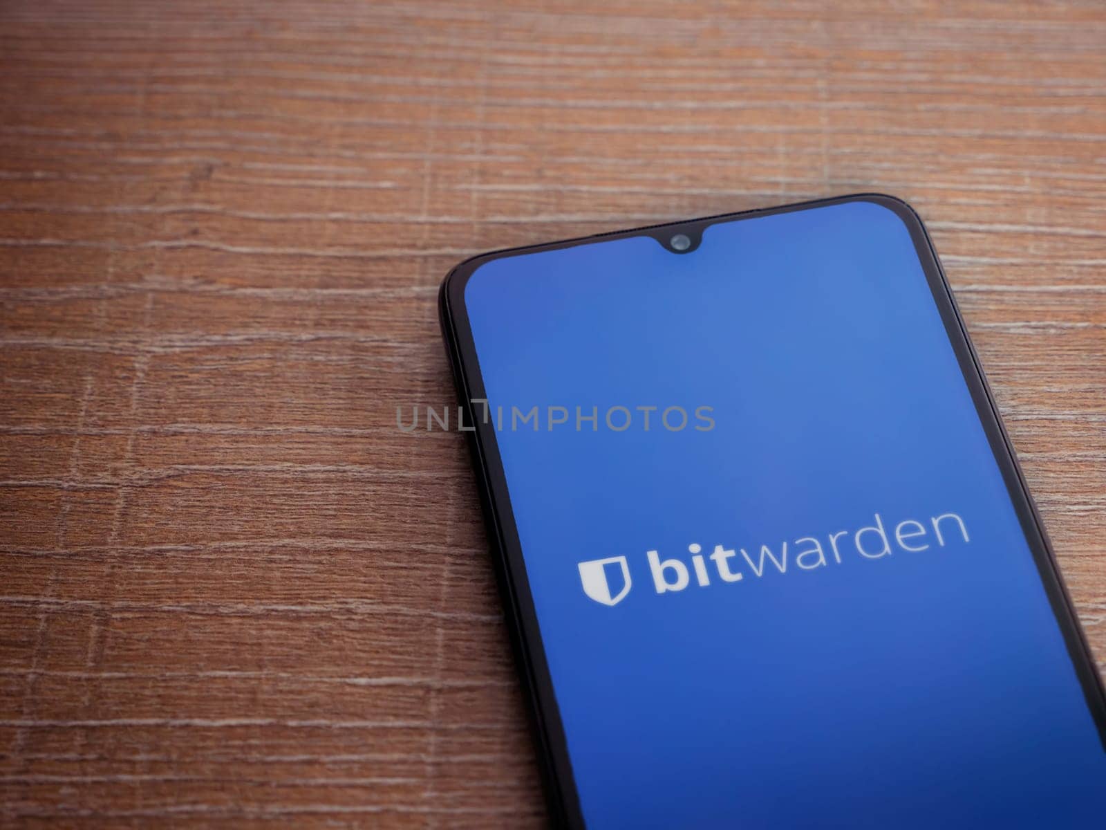Lod, Israel - July 16,2023: Bitwarden Password Manager app launch screen on smartphone on wooden background. Top view flat lay with copy space.