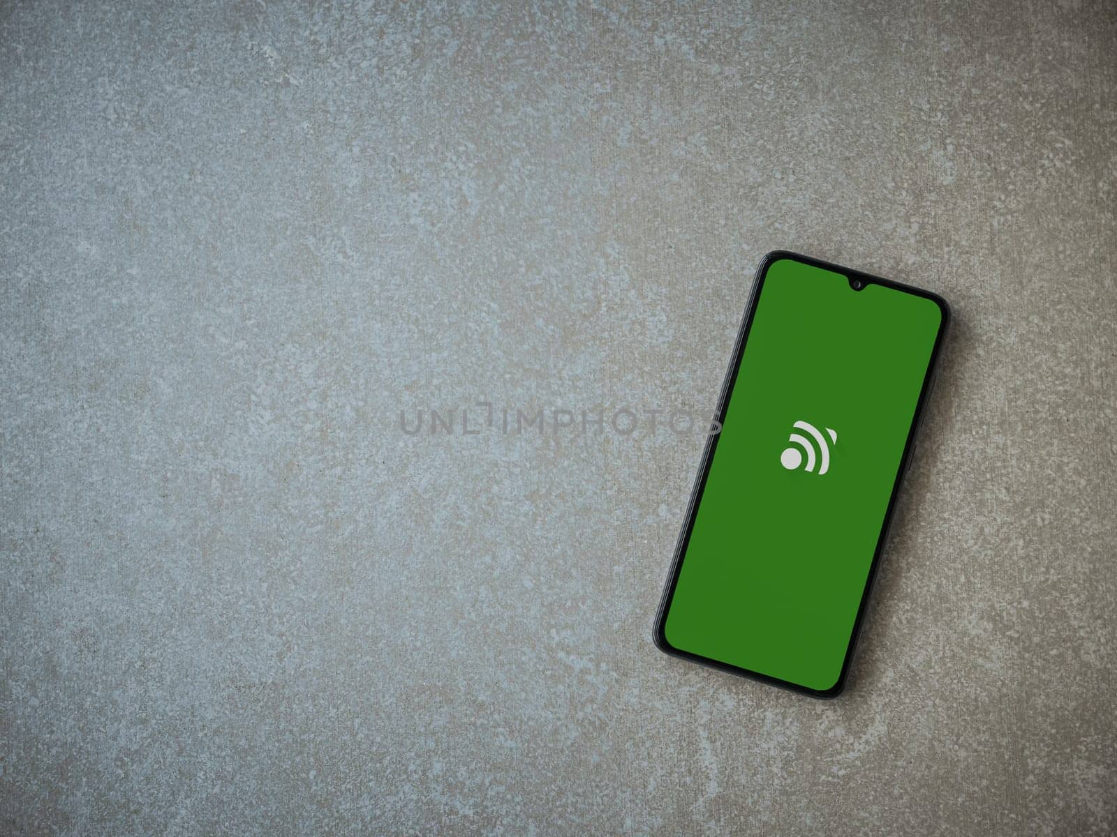 Lod, Israel - July 16,2023: Unified Remote app launch screen on smartphone on ceramic stone background. Top view flat lay with copy space.