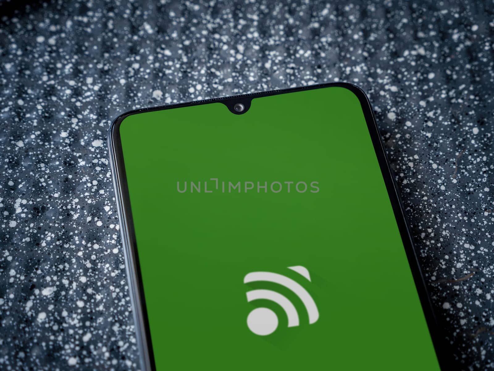 Lod, Israel - July 16,2023: Unified Remote app launch screen on smartphone on metallic background. Close up top view flat lay.