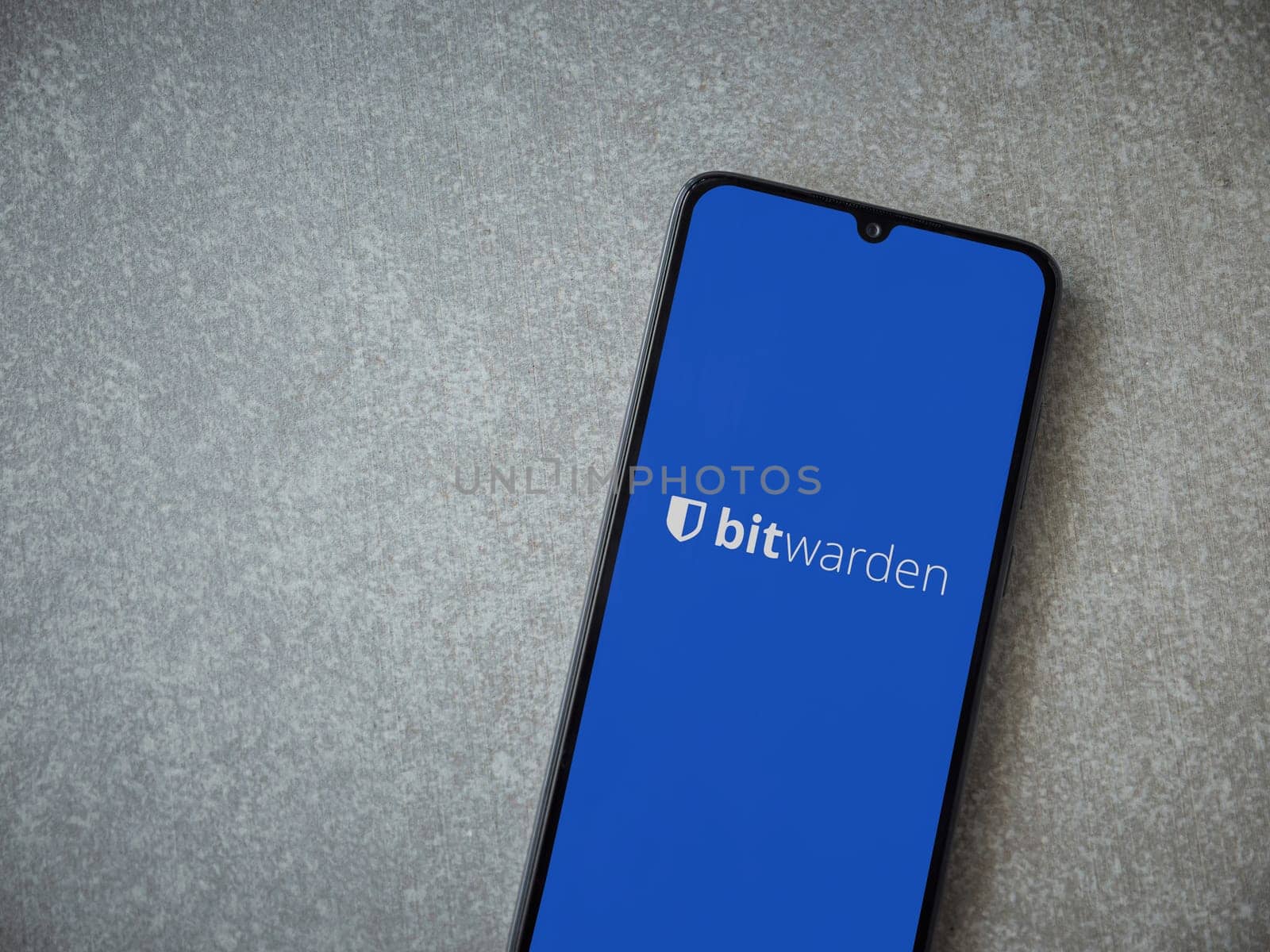 Lod, Israel - July 16,2023: Bitwarden Password Manager app launch screen on smartphone on ceramic stone background. Top view flat lay with copy space.