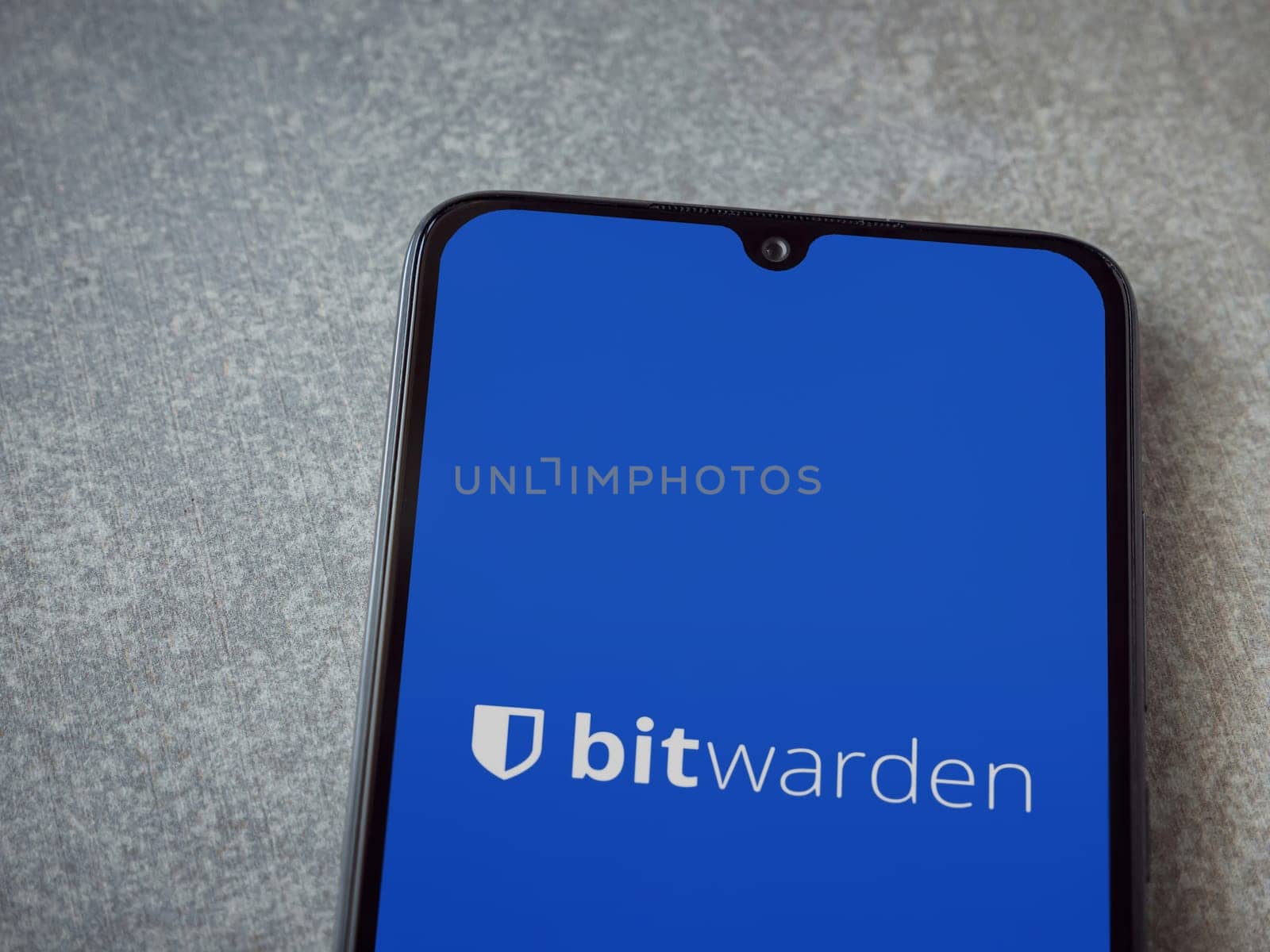 Lod, Israel - July 16,2023: Bitwarden Password Manager app launch screen on smartphone on ceramic stone background. Top view flat lay with copy space.