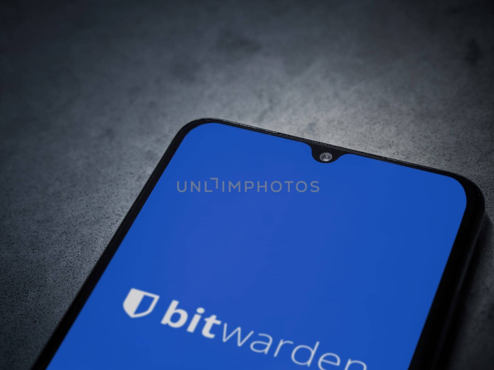 Lod, Israel - July 16,2023: Bitwarden Password Manager app launch screen on smartphone on dark marble stone background. Top view flat lay with copy space.