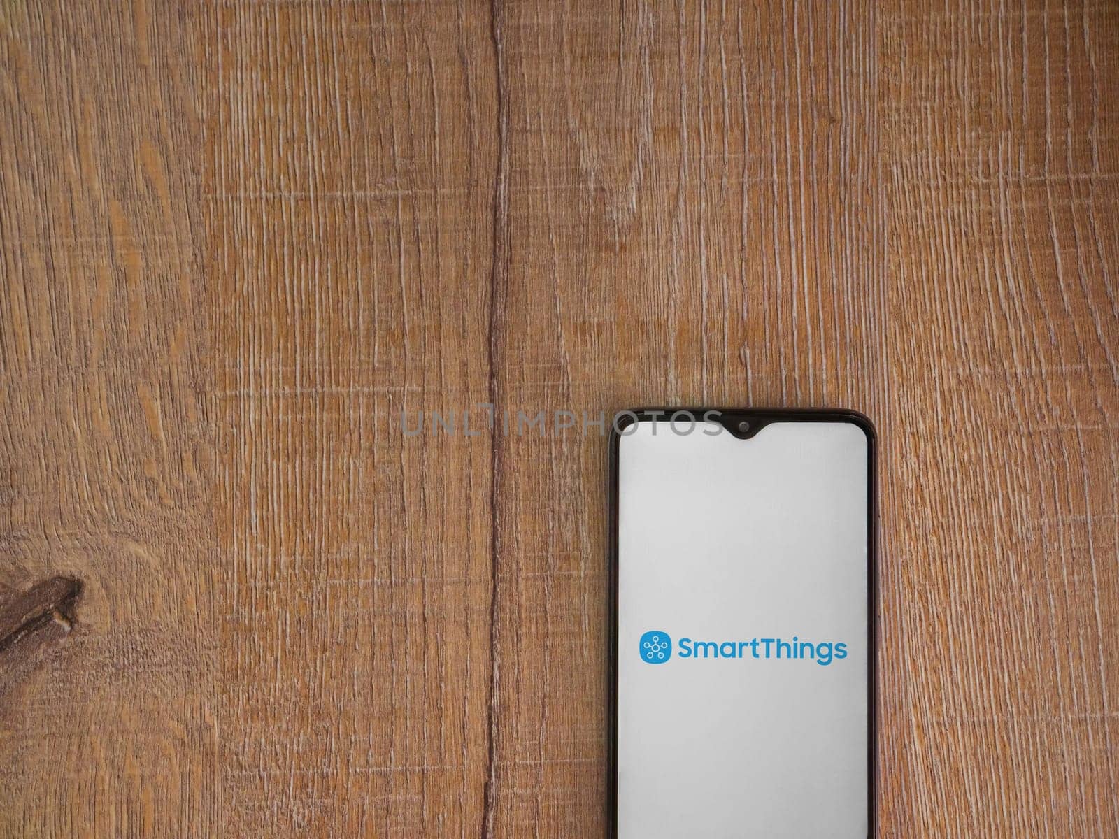 Lod, Israel - July 16,2023: Smartthings app launch screen on smartphone on wooden background. Top view flat lay with copy space.