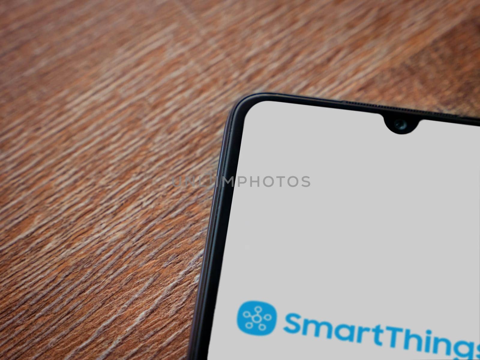 Lod, Israel - July 16,2023: Smartthings app launch screen on smartphone on wooden background. Top view flat lay with copy space.