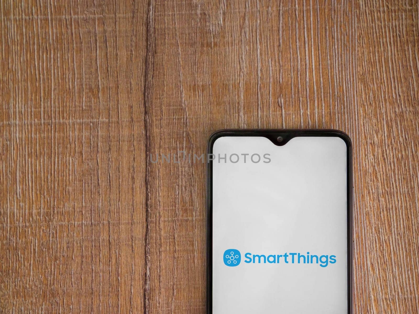 Lod, Israel - July 16,2023: Smartthings app launch screen on smartphone on wooden background. Top view flat lay with copy space.