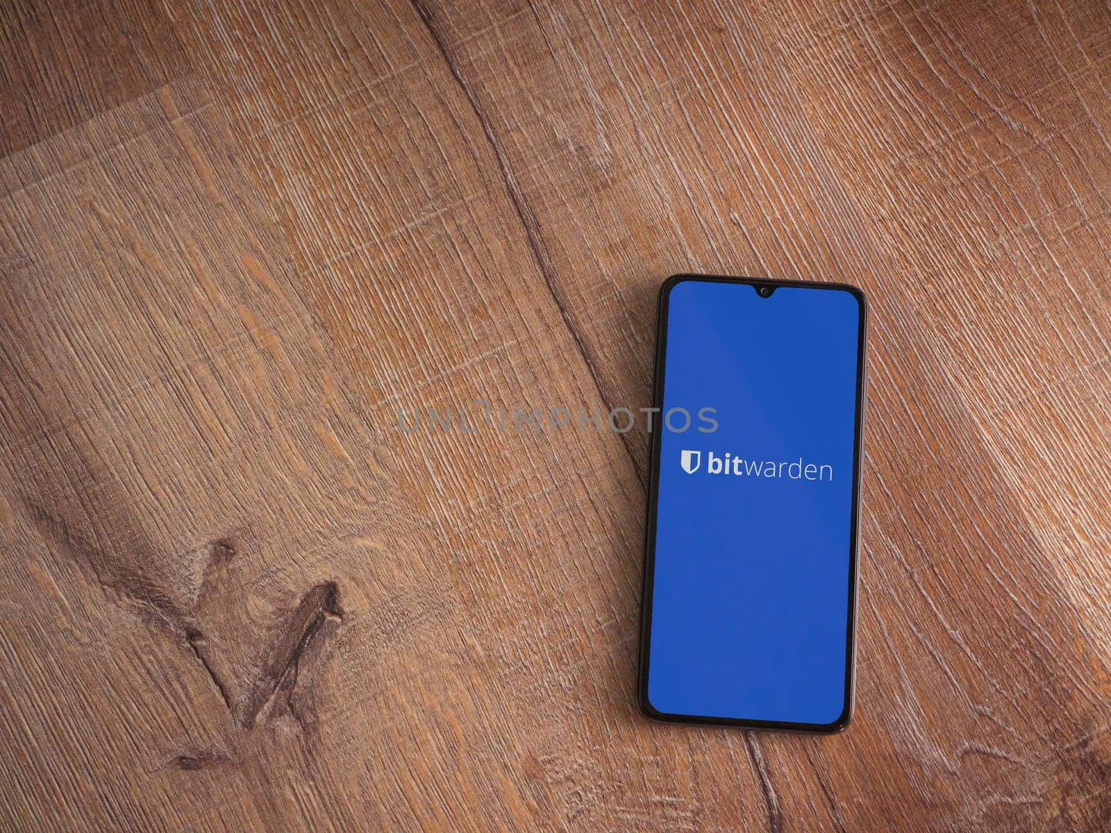 Lod, Israel - July 16,2023: Bitwarden Password Manager app launch screen on smartphone on wooden background. Top view flat lay with copy space.