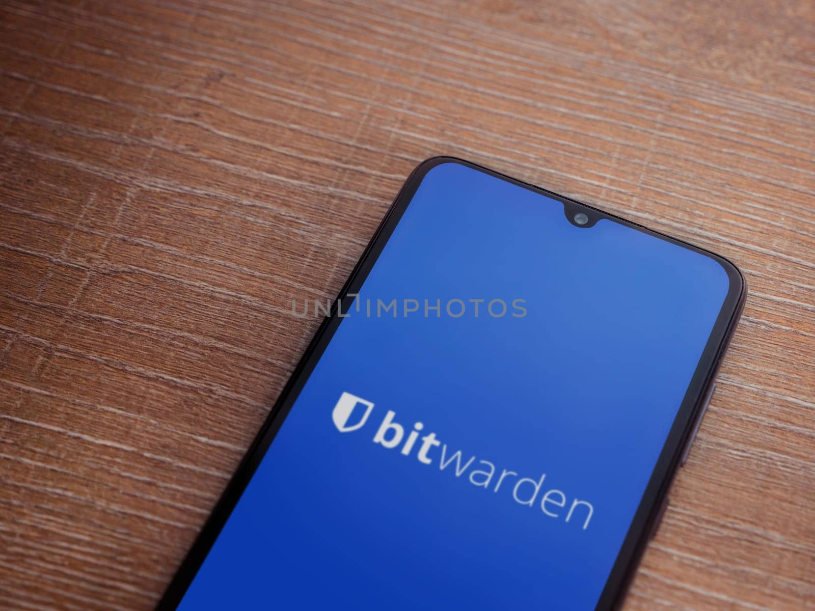 Lod, Israel - July 16,2023: Bitwarden Password Manager app launch screen on smartphone on wooden background. Top view flat lay with copy space.
