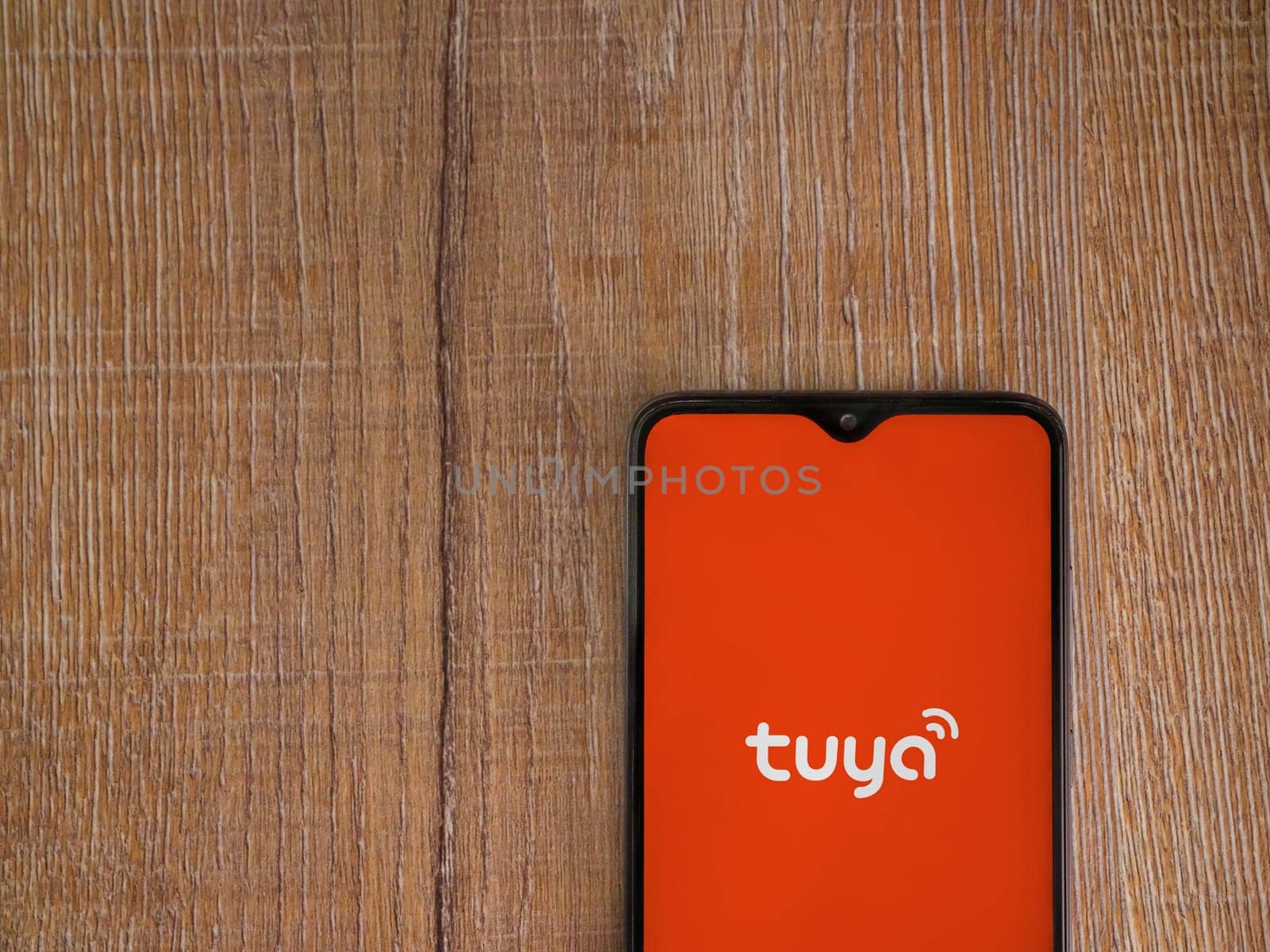 Lod, Israel - July 16,2023: Tuya Smart app launch screen on smartphone on wooden background. Top view flat lay with copy space.