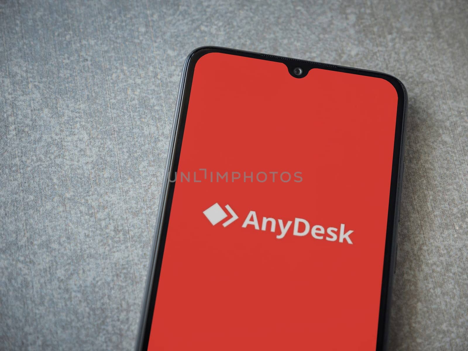 Lod, Israel - July 16,2023: Anydesk app launch screen on smartphone on ceramic stone background. Top view flat lay with copy space.