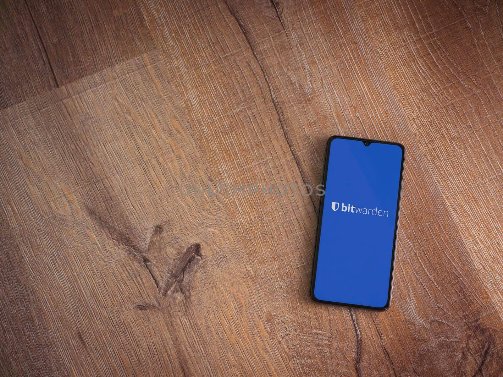 Lod, Israel - July 16,2023: Bitwarden Password Manager app launch screen on smartphone on wooden background. Top view flat lay with copy space.