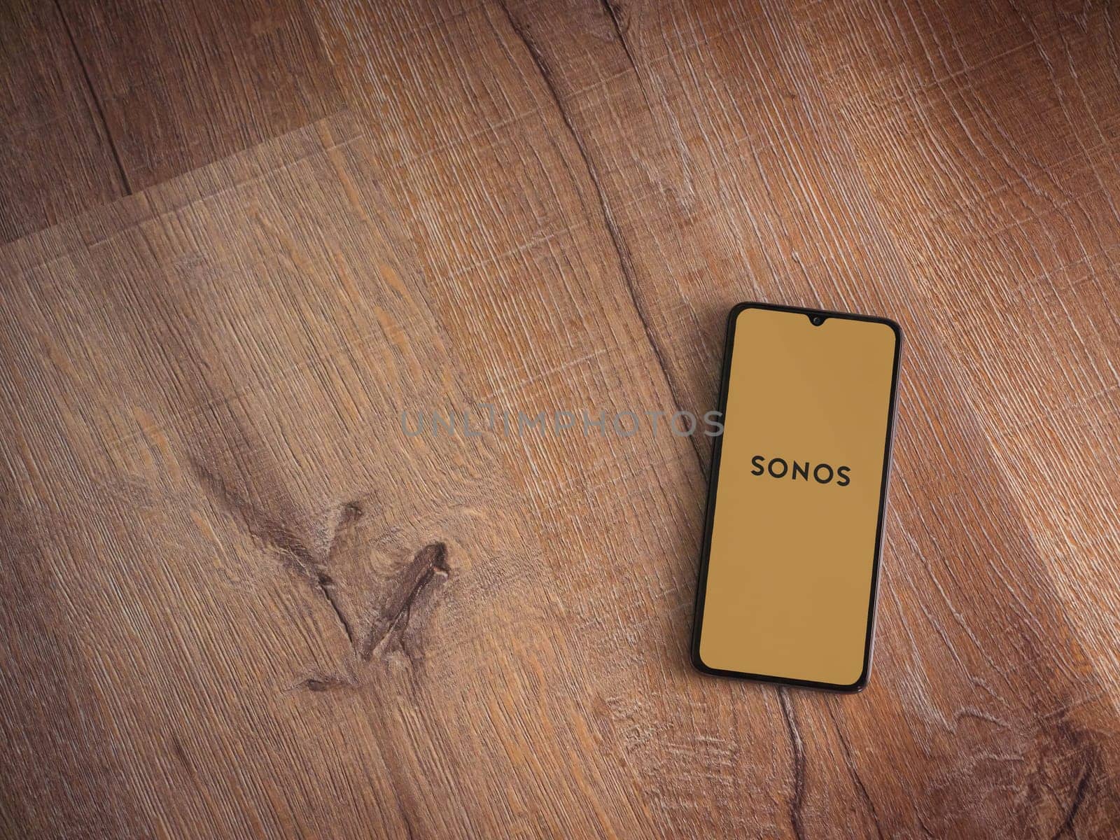 Lod, Israel - July 16,2023: Sonos app launch screen on smartphone on wooden background. Top view flat lay with copy space.