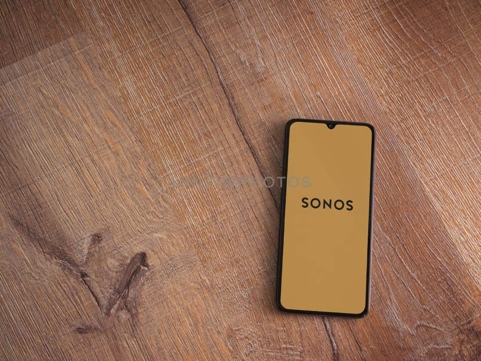 Lod, Israel - July 16,2023: Sonos app launch screen on smartphone on wooden background. Top view flat lay with copy space.