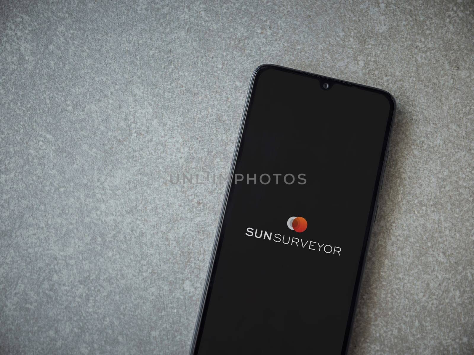 Lod, Israel - July 16,2023: Sun Surveyor app launch screen on smartphone on ceramic stone background. Top view flat lay with copy space.
