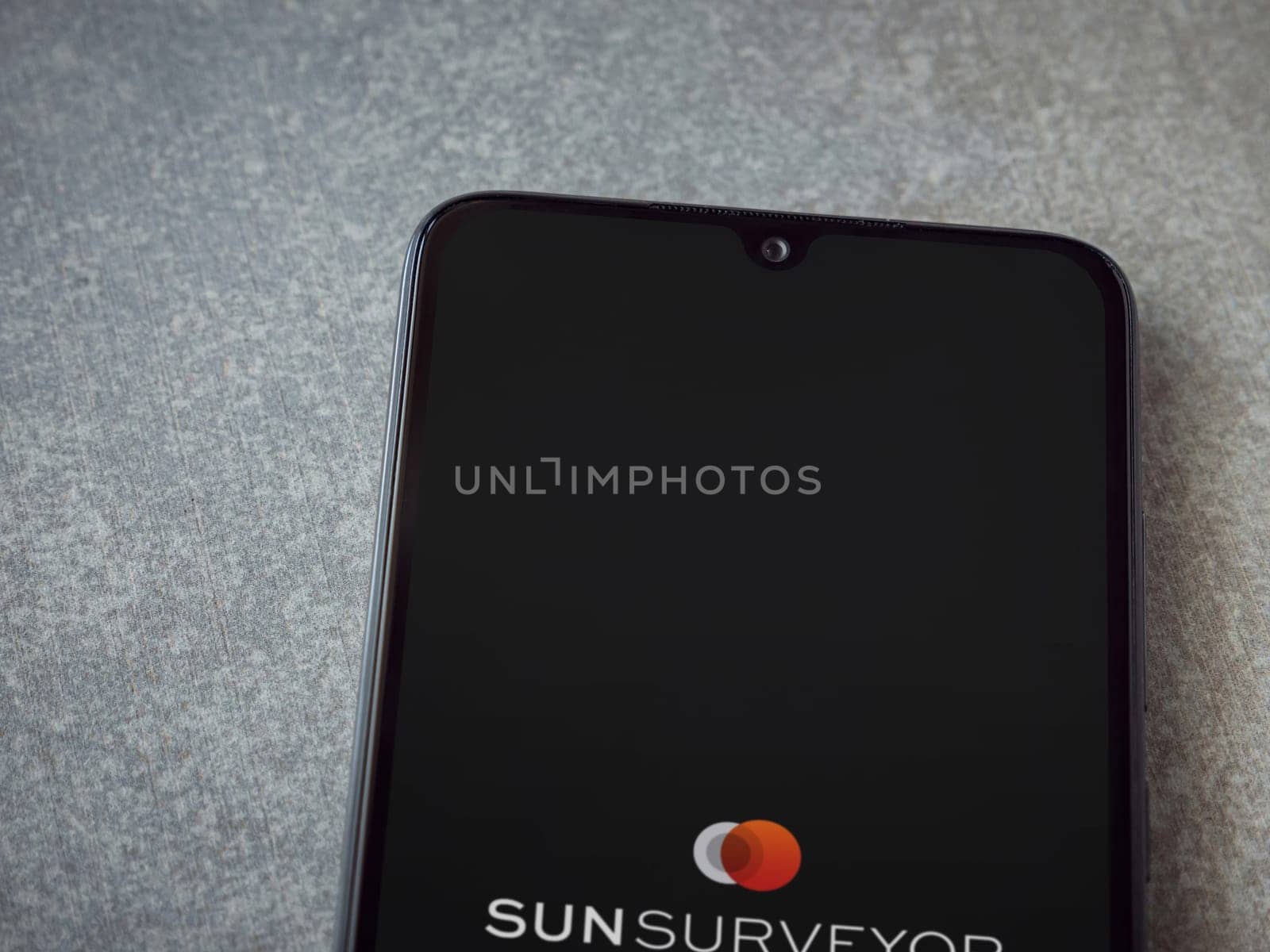 Lod, Israel - July 16,2023: Sun Surveyor app launch screen on smartphone on ceramic stone background. Top view flat lay with copy space.