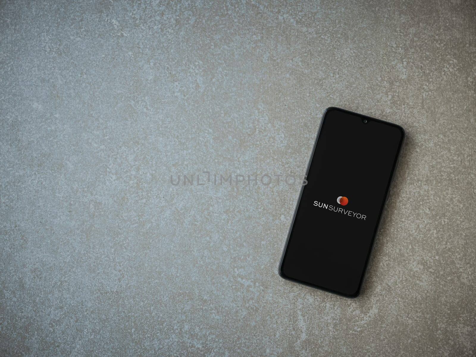 Lod, Israel - July 16,2023: Sun Surveyor app launch screen on smartphone on ceramic stone background. Top view flat lay with copy space.