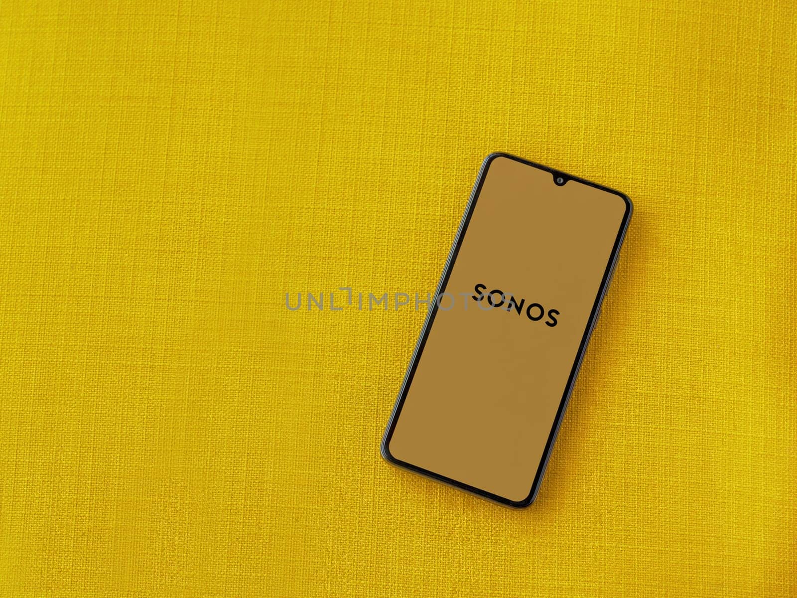Lod, Israel - July 16,2023: Sonos app launch screen on smartphone on yellow fabric background. Top view flat lay with copy space.