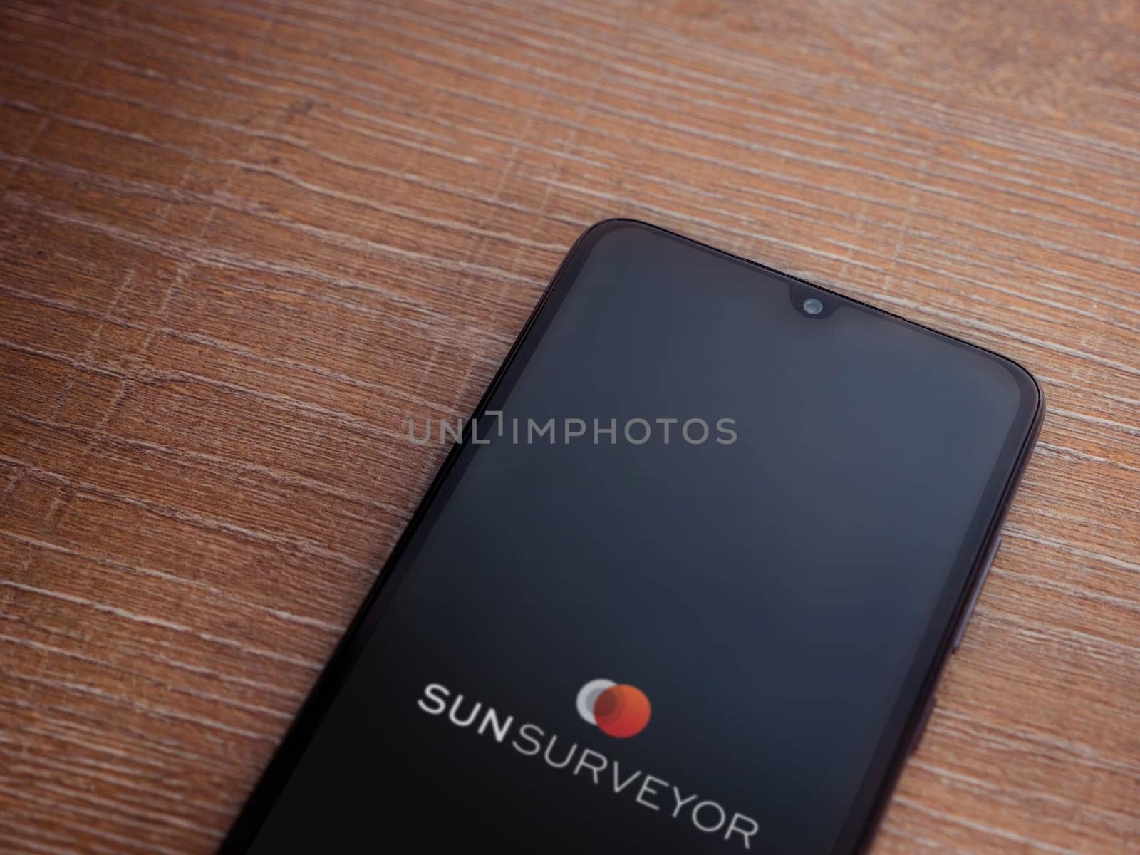 Lod, Israel - July 16,2023: Sun Surveyor app launch screen on smartphone on wooden background. Top view flat lay with copy space.