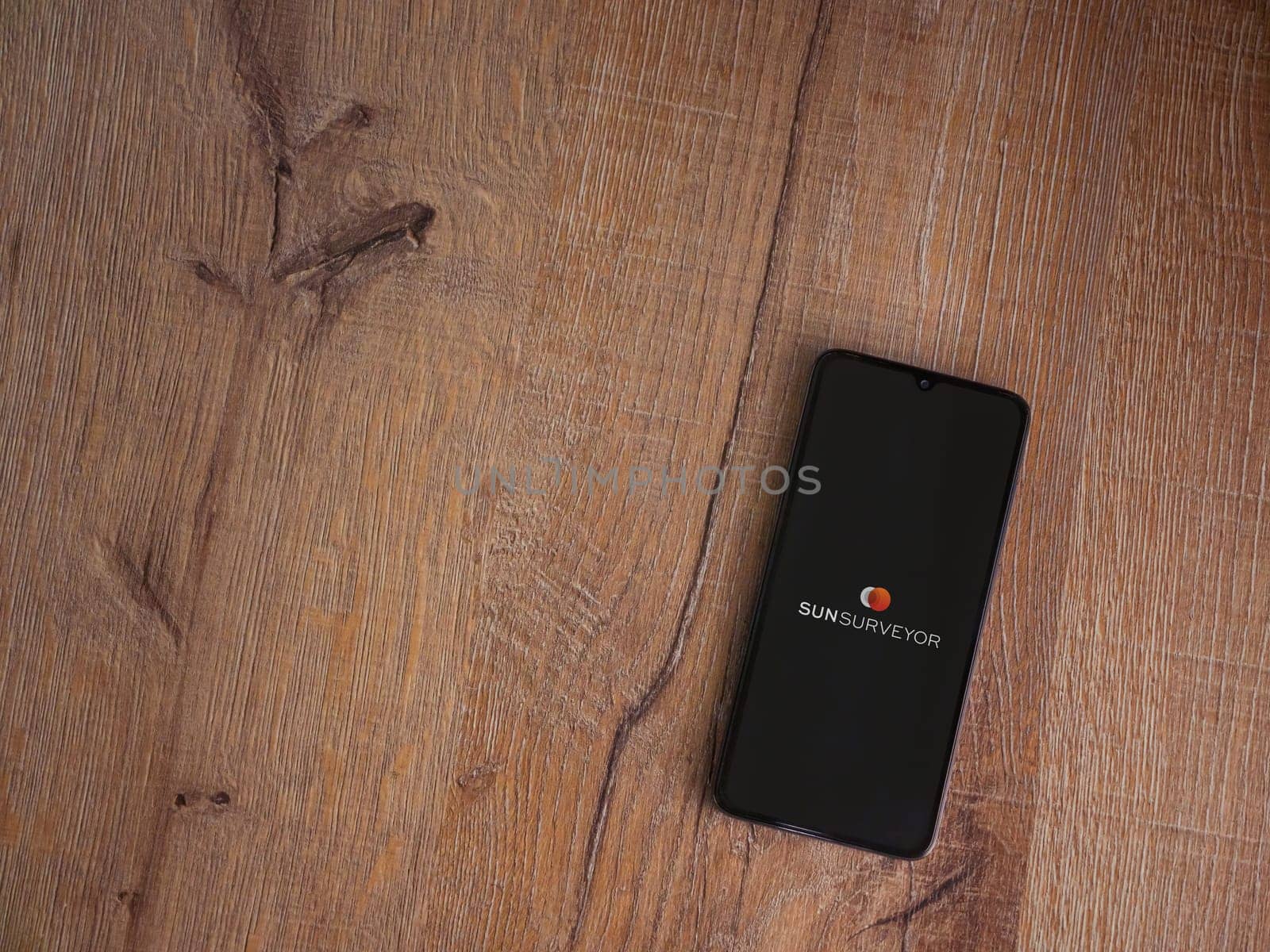 Lod, Israel - July 16,2023: Sun Surveyor app launch screen on smartphone on wooden background. Top view flat lay with copy space.