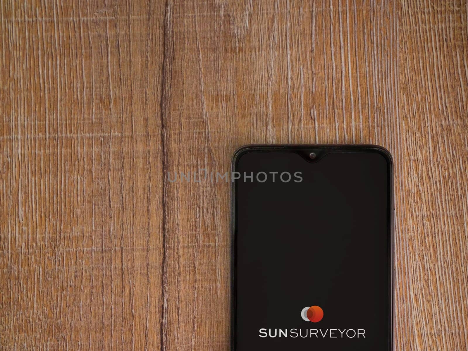 Lod, Israel - July 16,2023: Sun Surveyor app launch screen on smartphone on wooden background. Top view flat lay with copy space.