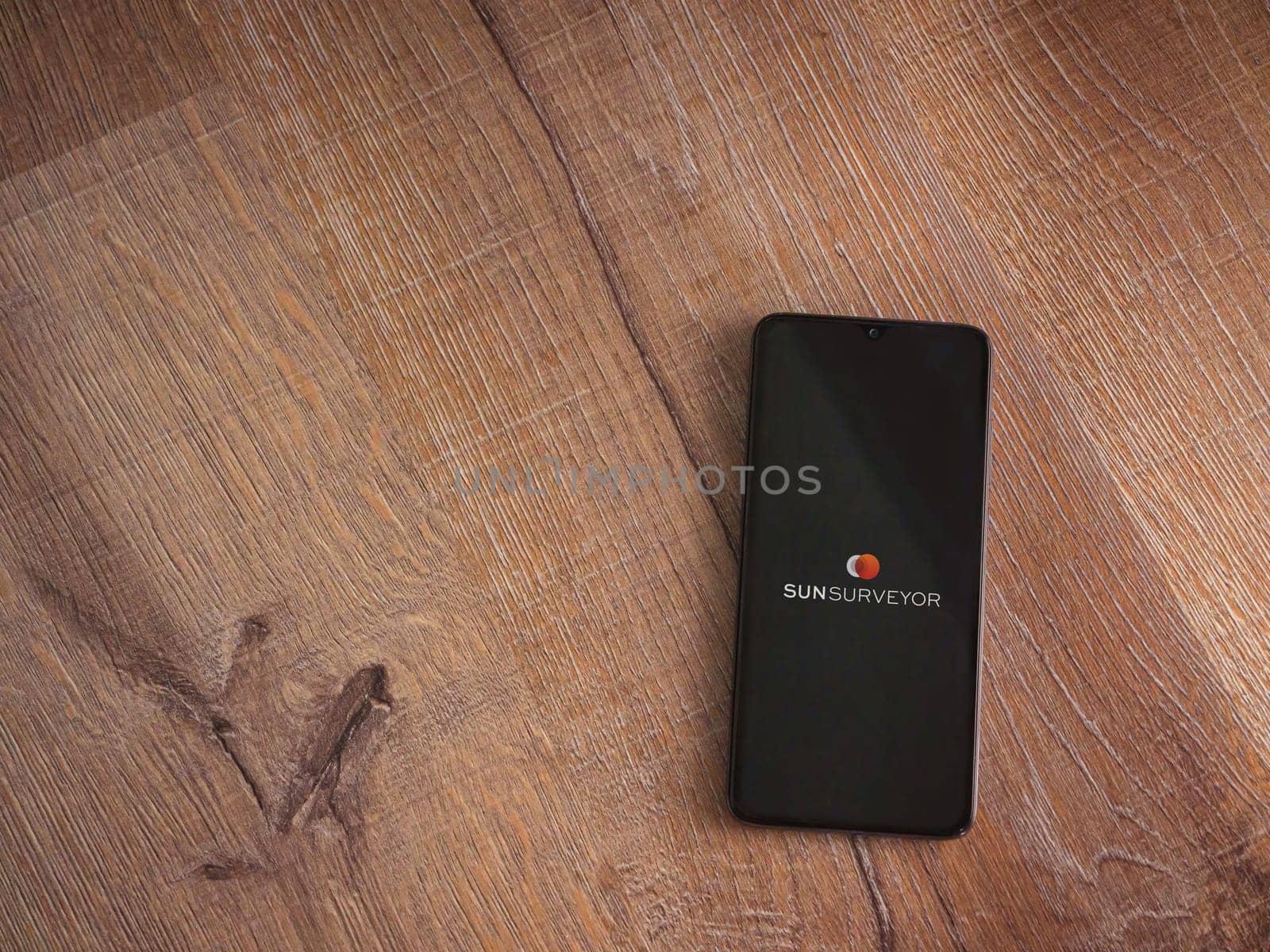 Lod, Israel - July 16,2023: Sun Surveyor app launch screen on smartphone on wooden background. Top view flat lay with copy space.