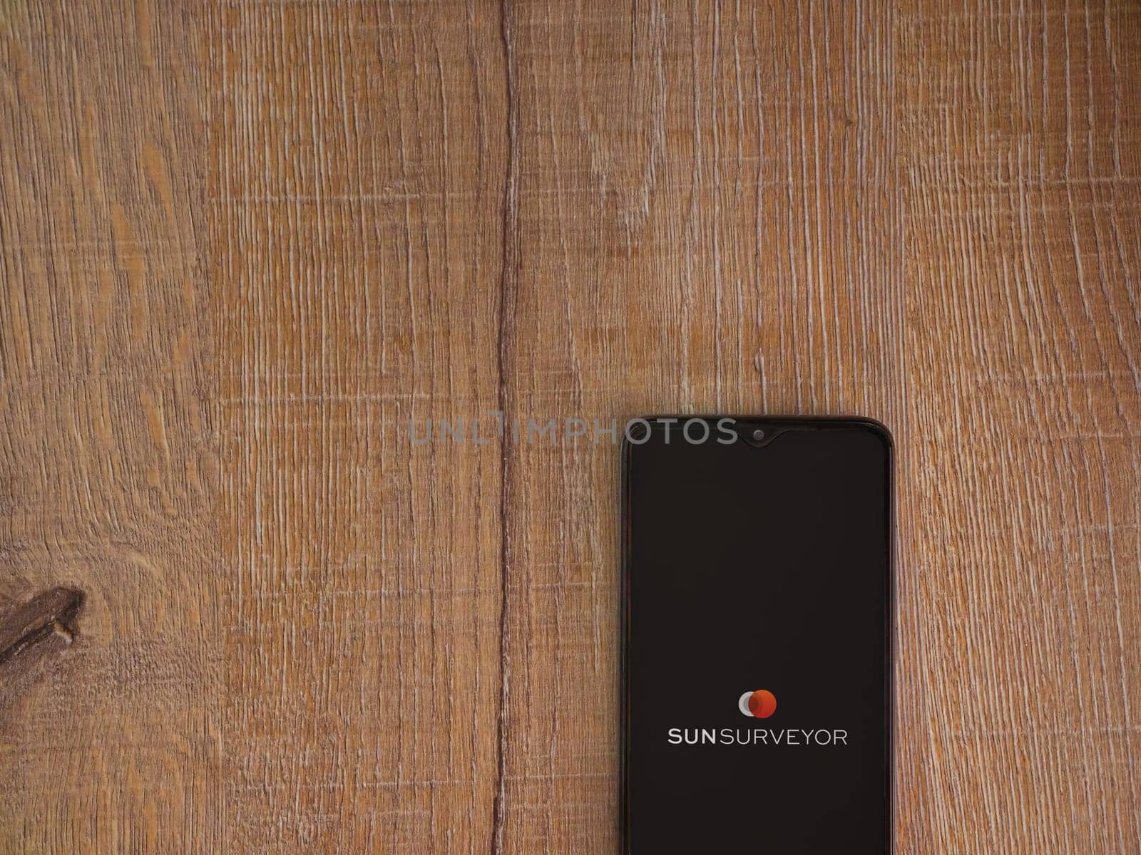 Lod, Israel - July 16,2023: Sun Surveyor app launch screen on smartphone on wooden background. Top view flat lay with copy space.
