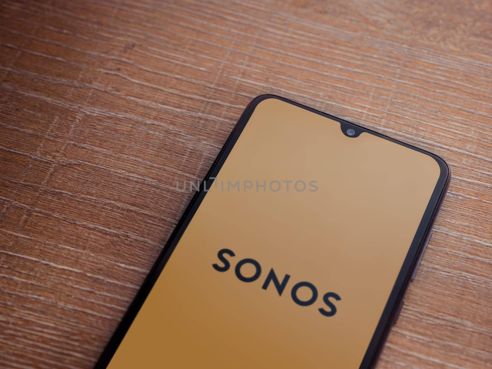 Lod, Israel - July 16,2023: Sonos app launch screen on smartphone on wooden background. Top view flat lay with copy space.
