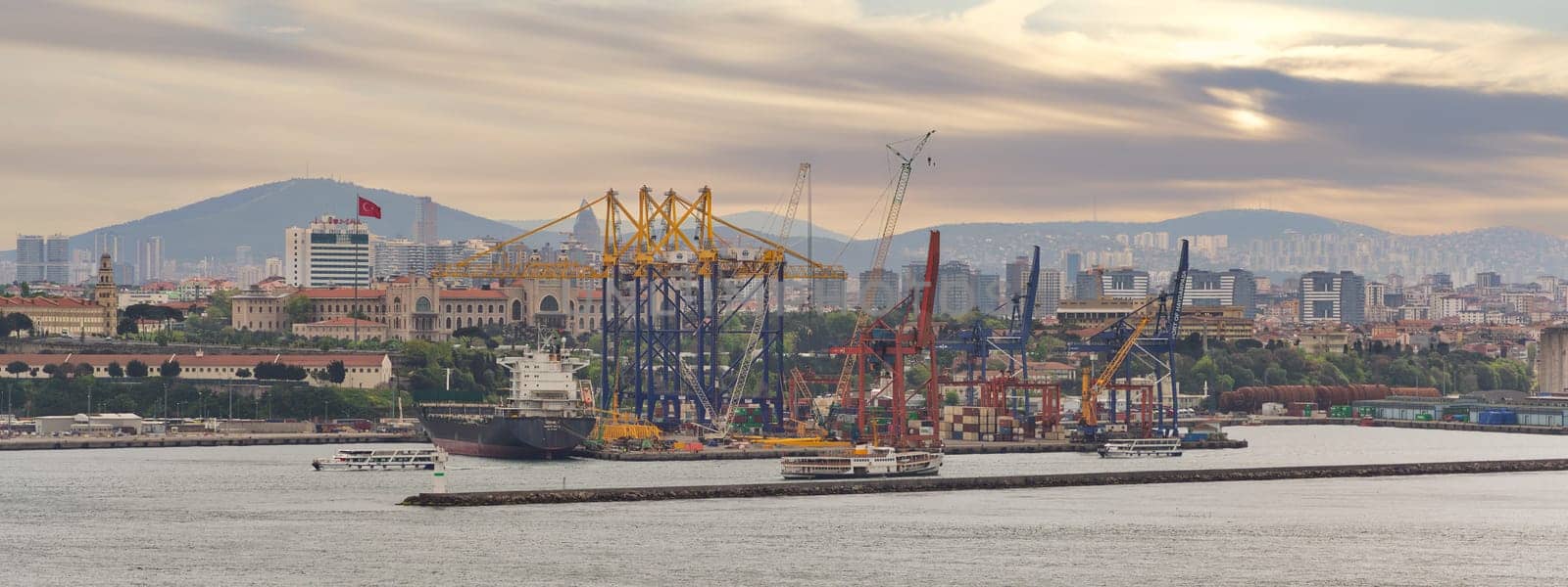 Istanbul, Turkey - May 11, 2023: Beautiful sunrise over Haydarpasa Port, with cargo ships and cranes silhouetted against the sky. Water reflects the colors of the sunrise, View from Topkapi Palace