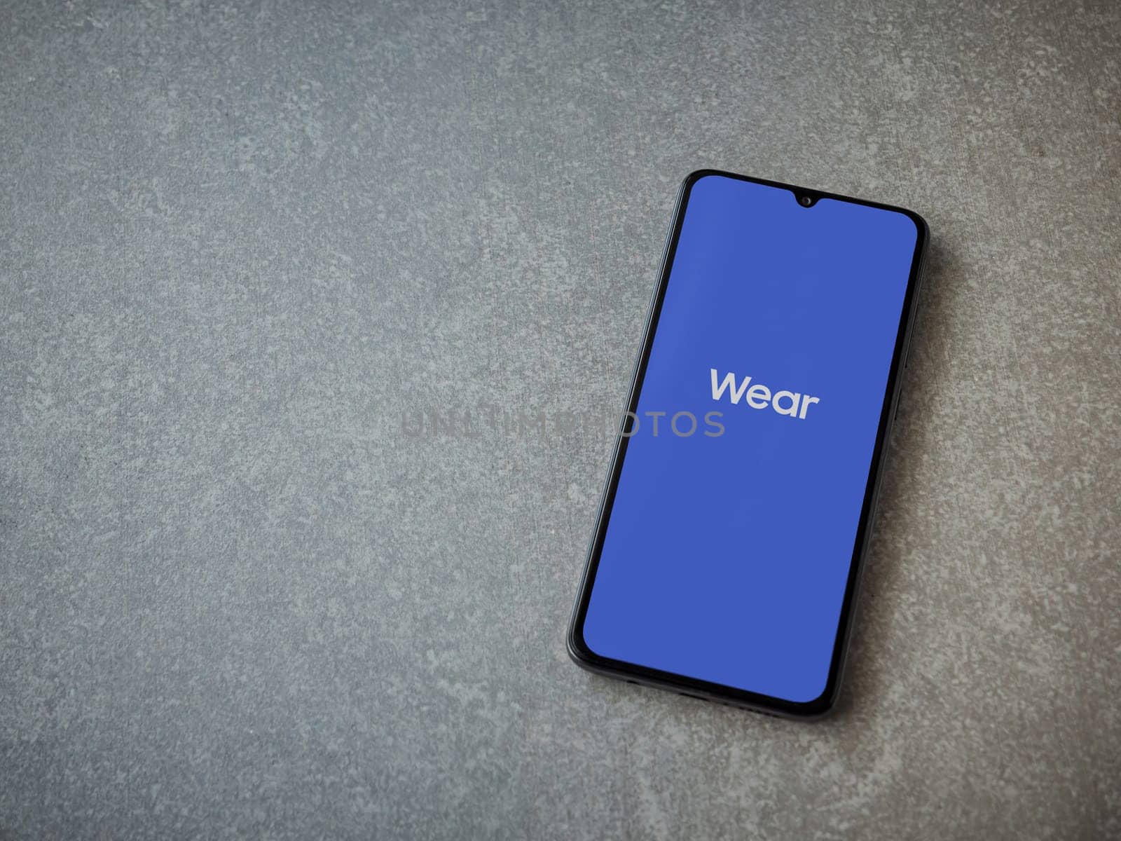 Lod, Israel - July 16,2023: Wear - Galaxy Wearable app launch screen on smartphone on ceramic stone background. Top view flat lay with copy space.