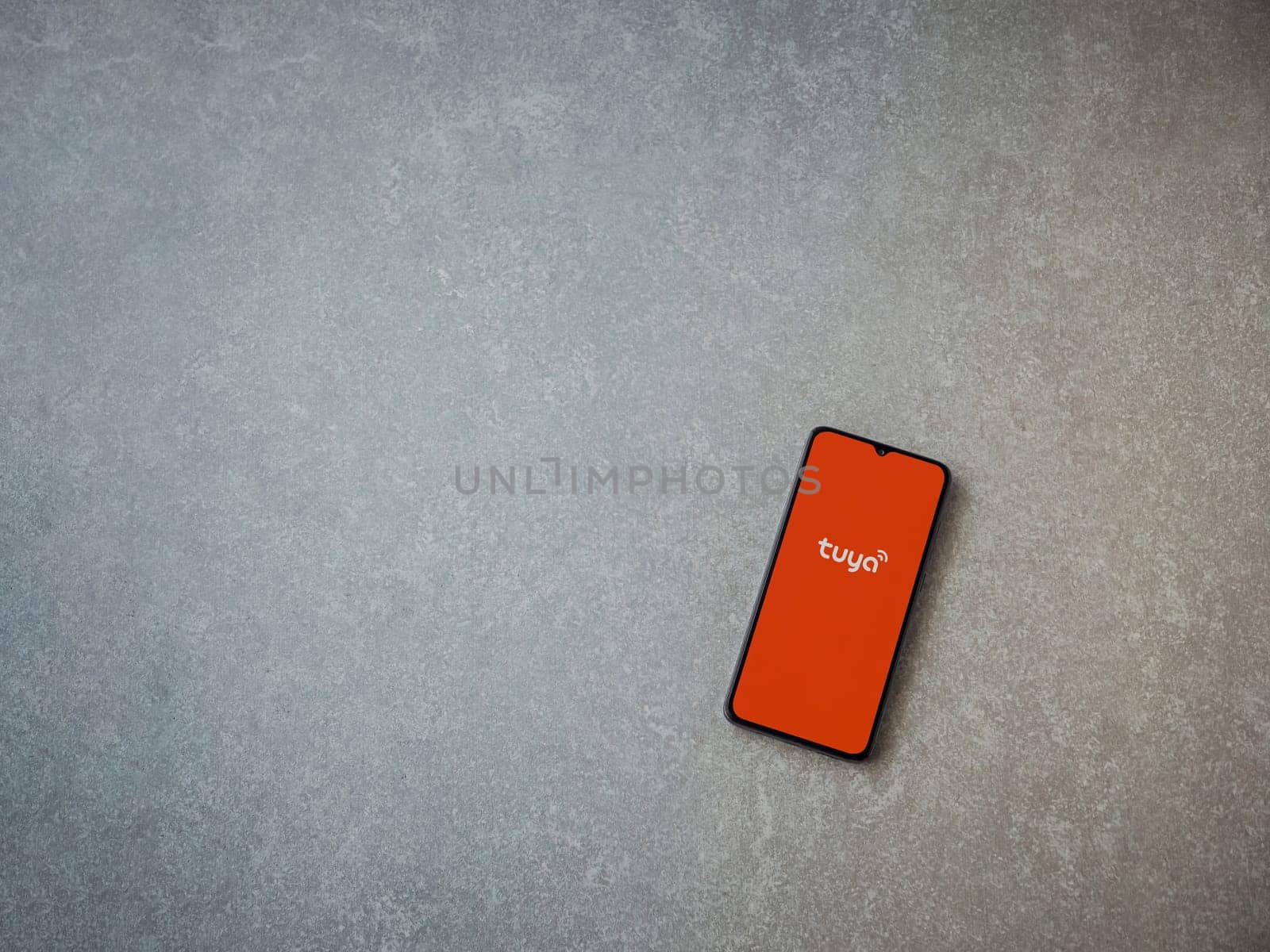 Lod, Israel - July 16,2023: Tuya Smart app launch screen on smartphone on ceramic stone background. Top view flat lay with copy space.