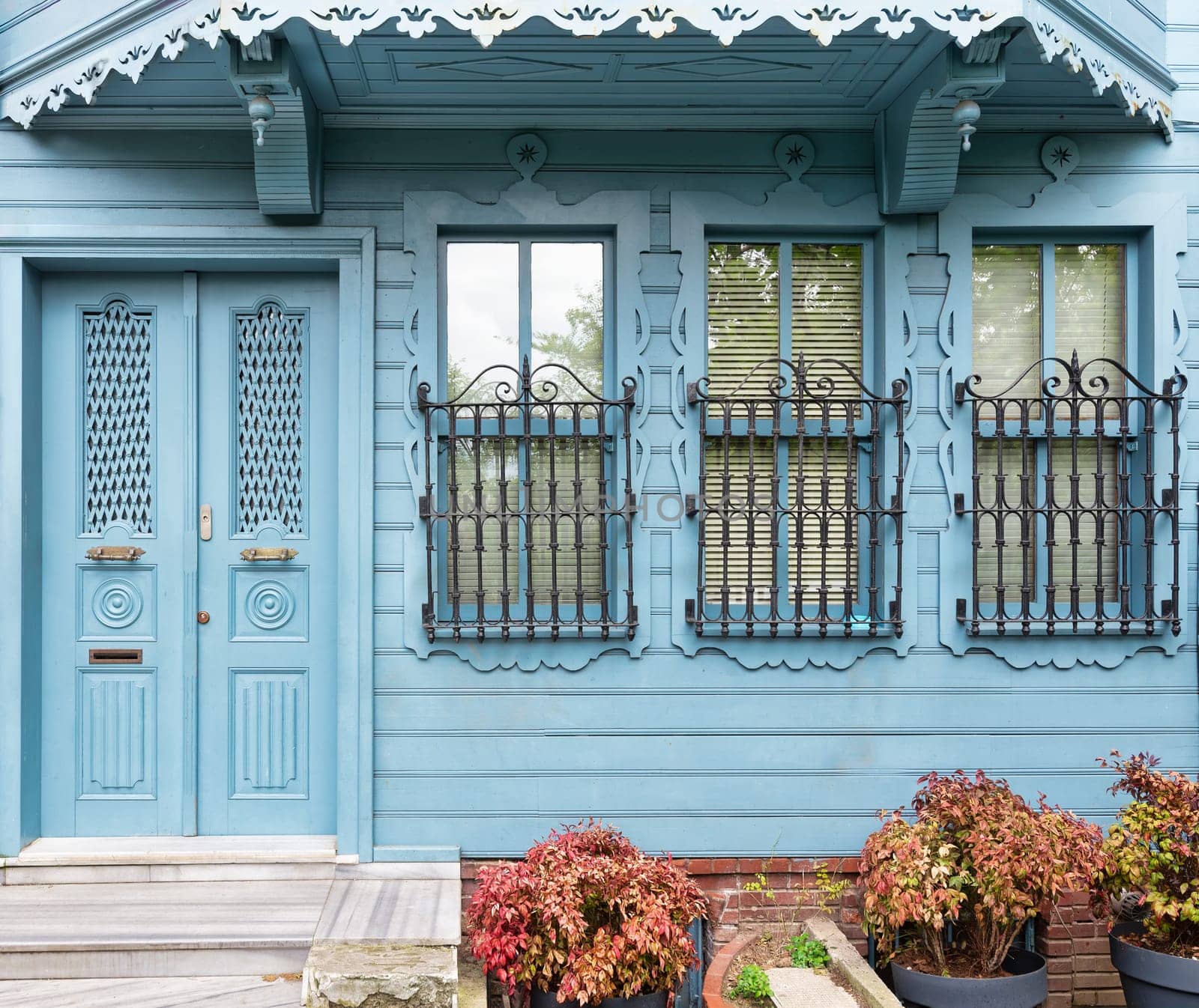 Charming blue house with wooden decorated door and ornate wrought iron windows. The house is located at an alley suited in Kuzguncuk neighborhood, Uskudar district, Istanbul, Turkey