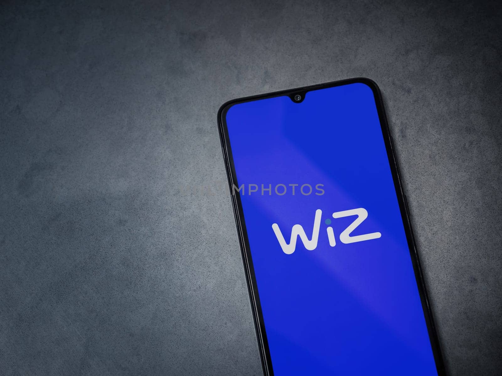Lod, Israel - July 16,2023: WIZ app launch screen on smartphone on dark marble stone background. Top view flat lay with copy space.