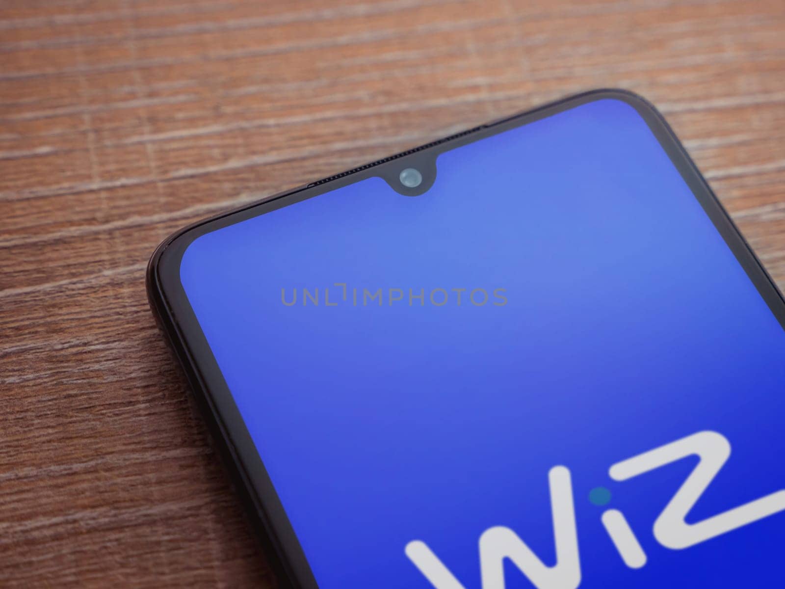 Lod, Israel - July 16,2023: WIZ app launch screen on smartphone on wooden background. Top view flat lay with copy space.