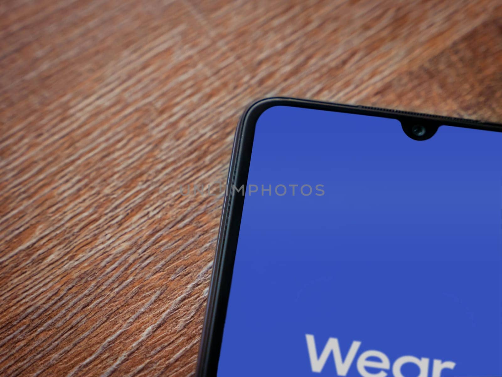 Lod, Israel - July 16,2023: Wear - Galaxy Wearable app launch screen on smartphone on wooden background. Top view flat lay with copy space.