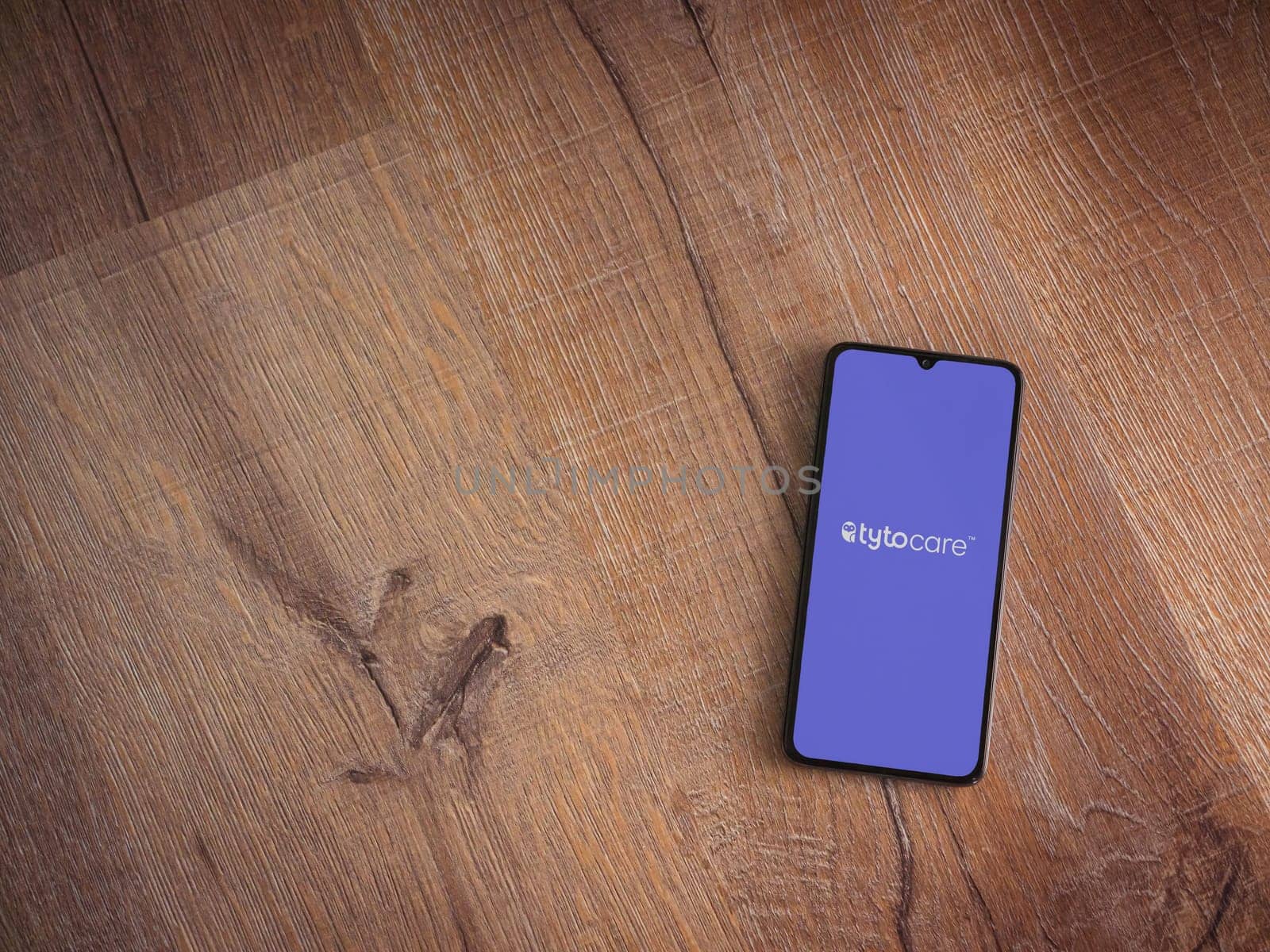 Lod, Israel - July 16,2023: TytoCare app launch screen on smartphone on wooden background. Top view flat lay with copy space.