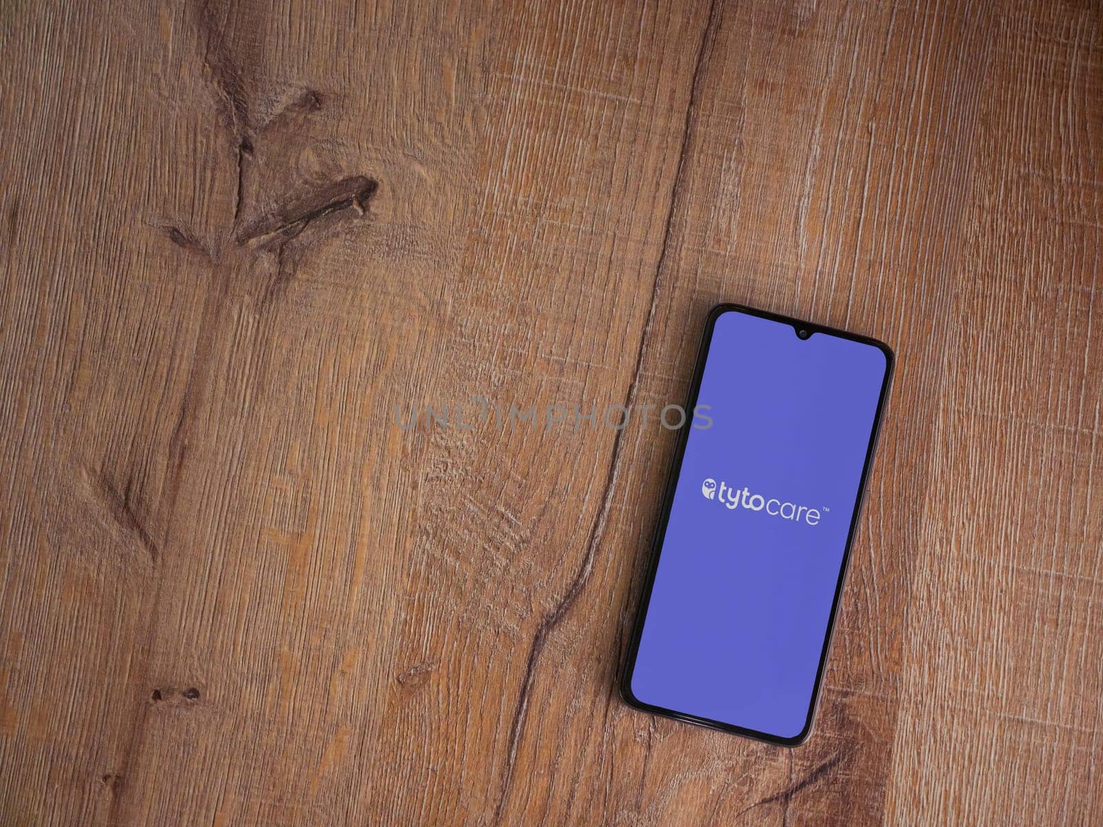 Lod, Israel - July 16,2023: TytoCare app launch screen on smartphone on wooden background. Top view flat lay with copy space.
