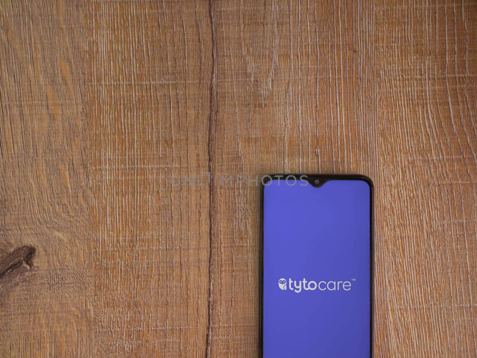 Lod, Israel - July 16,2023: TytoCare app launch screen on smartphone on wooden background. Top view flat lay with copy space.