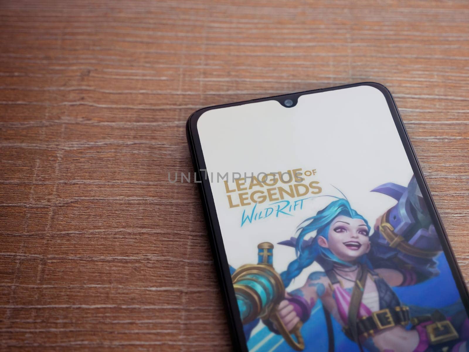 Lod, Israel - July 16,2023: League of Legends - Wild Rift app launch screen on smartphone on wooden background. Top view flat lay with copy space.