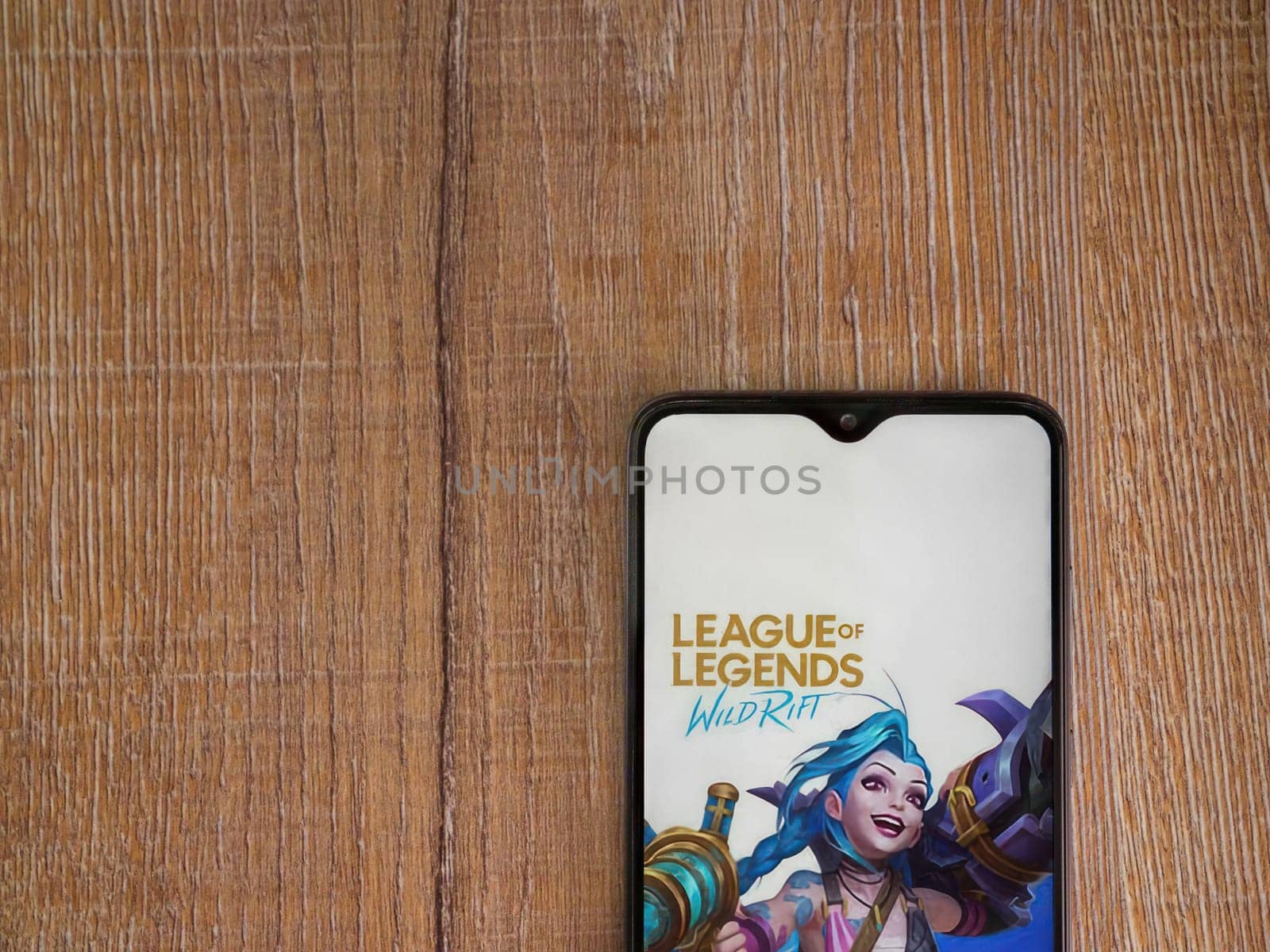 Lod, Israel - July 16,2023: League of Legends - Wild Rift app launch screen on smartphone on wooden background. Top view flat lay with copy space.