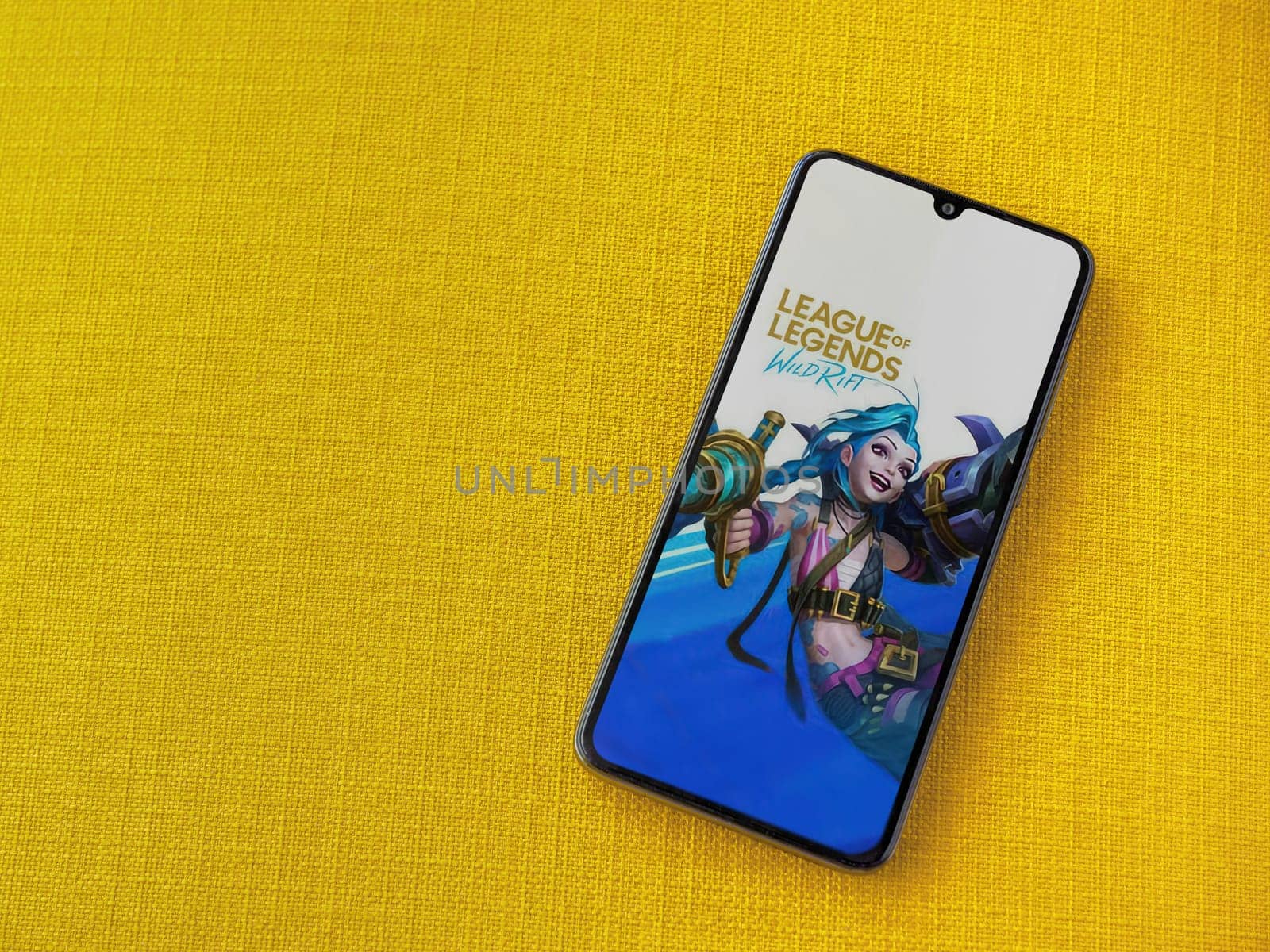 Lod, Israel - July 16,2023: League of Legends - Wild Rift app launch screen on smartphone on yellow fabric background. Top view flat lay with copy space.