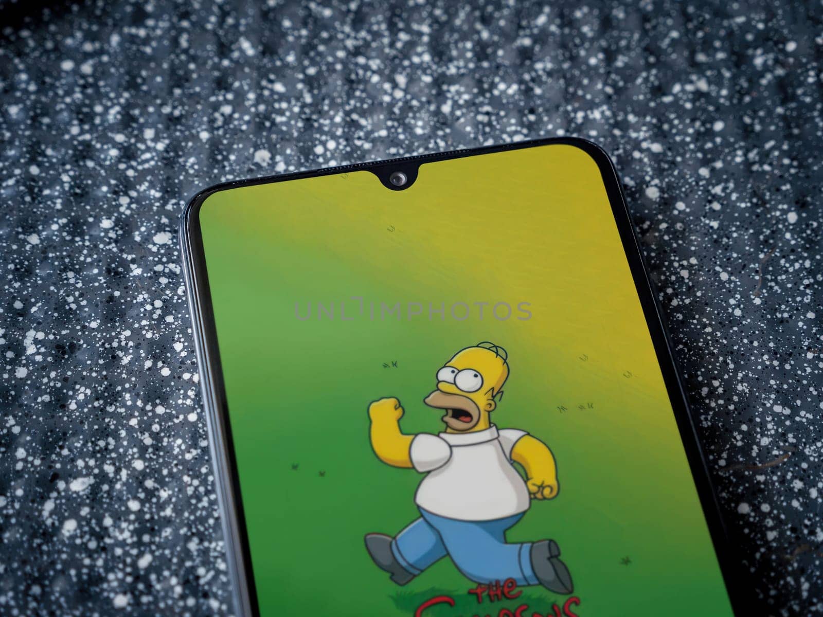 Lod, Israel - July 16,2023: The Simpsons Tapped Out app launch screen on smartphone on metallic background. Close up top view flat lay.
