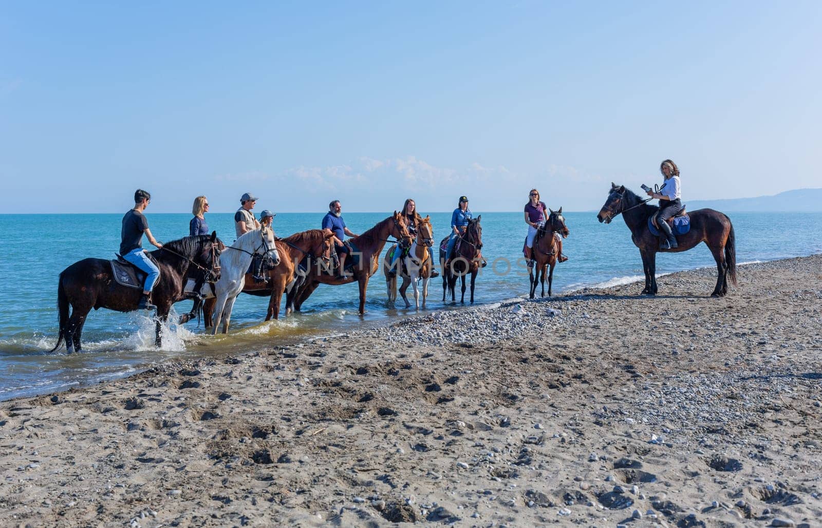 Policoro, Italy - 7 May 2023: People riding horses in a Policoro beach, Basilicata, southern Italy.