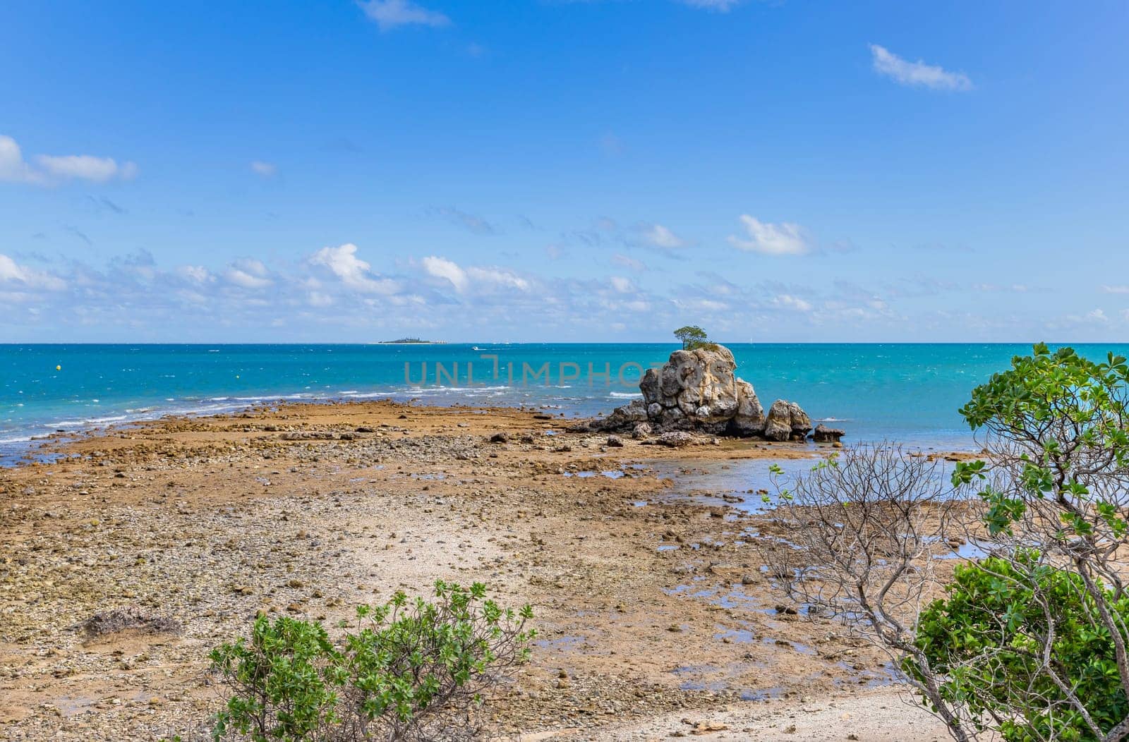 Sea stack at Rocher a la voile (Sailing Rock), historical landmark at Anse Vata Bay with Ile des Canards (Island of Ducks) in the background, in Noumea, New Caledonia, South Pacific Ocean.
