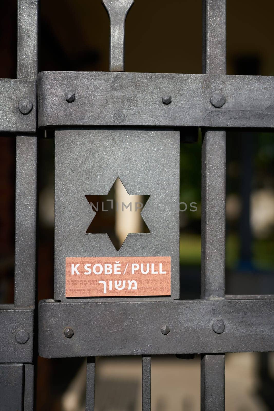 Entrance door to a Jewish cemetery in Prague with Star of David and notice to open the door in three languages