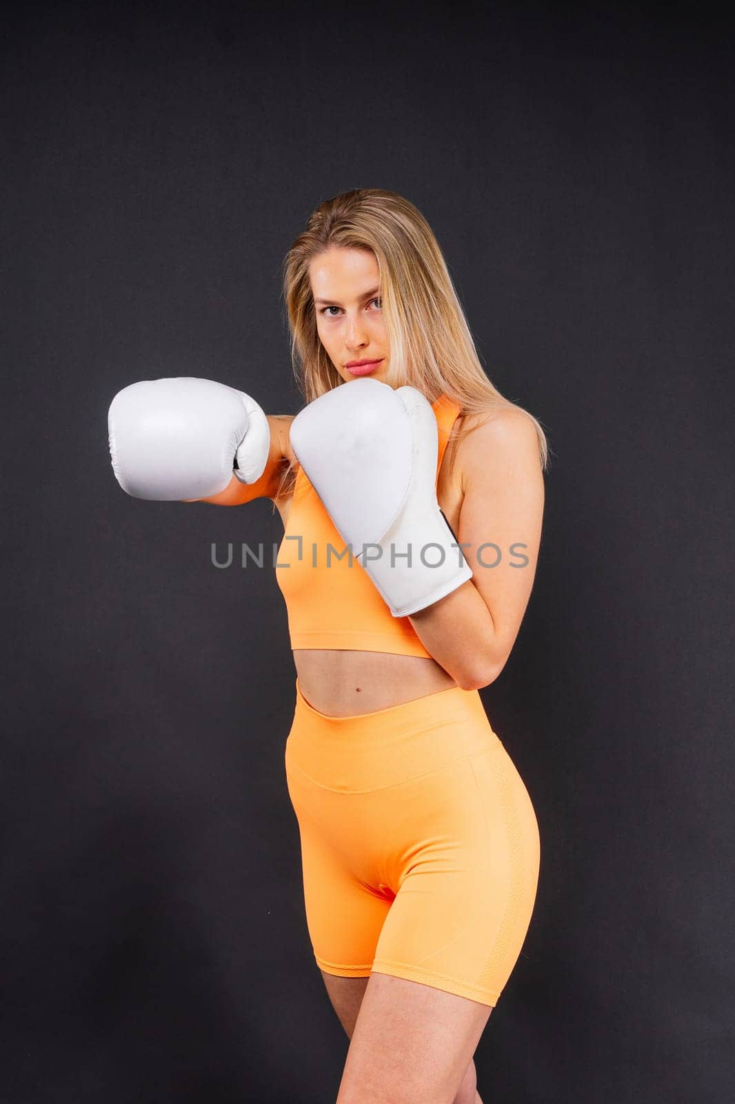 Woman boxer in gloves training on a yellow and dark studio background