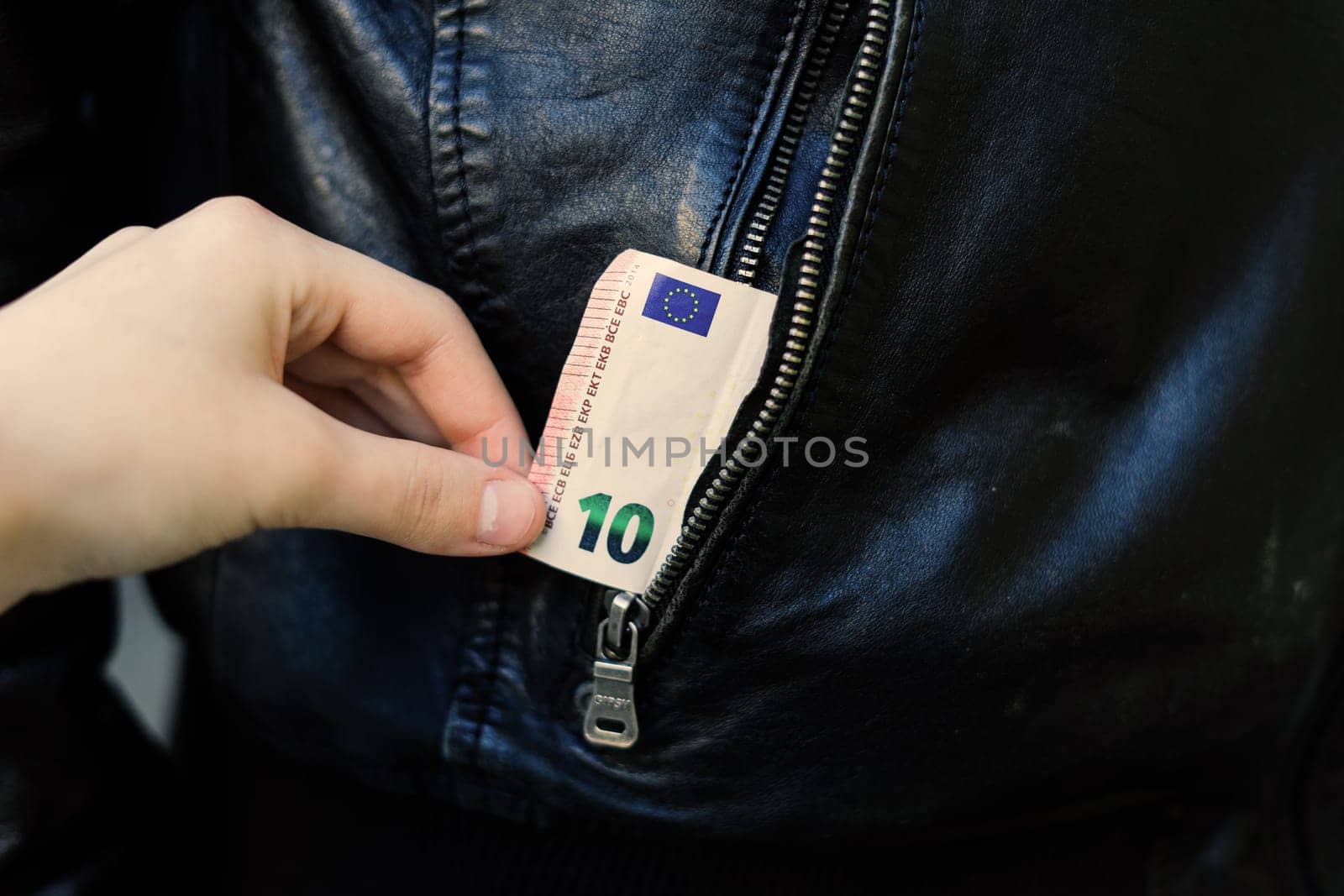 Hand pulls paper money and card out of pocket. A thief robbed man. Cash theft, criminal concept.