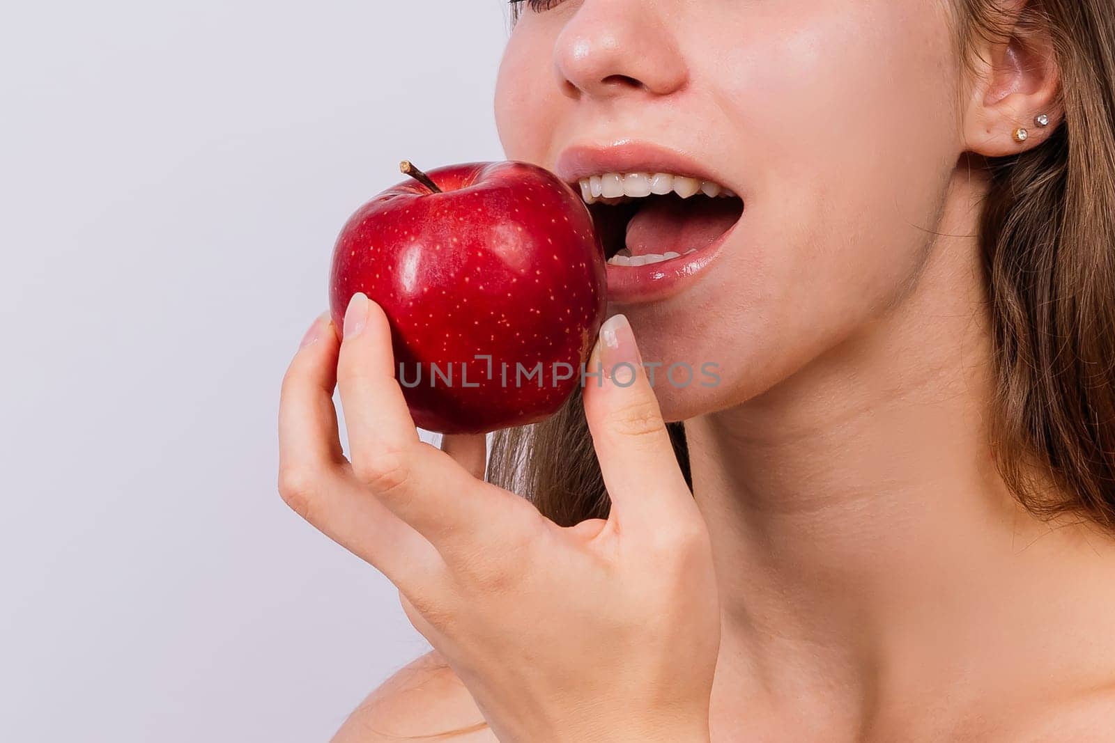 Morning breakfast. Woman with healthy teeth holding apples on a grey isolated background.