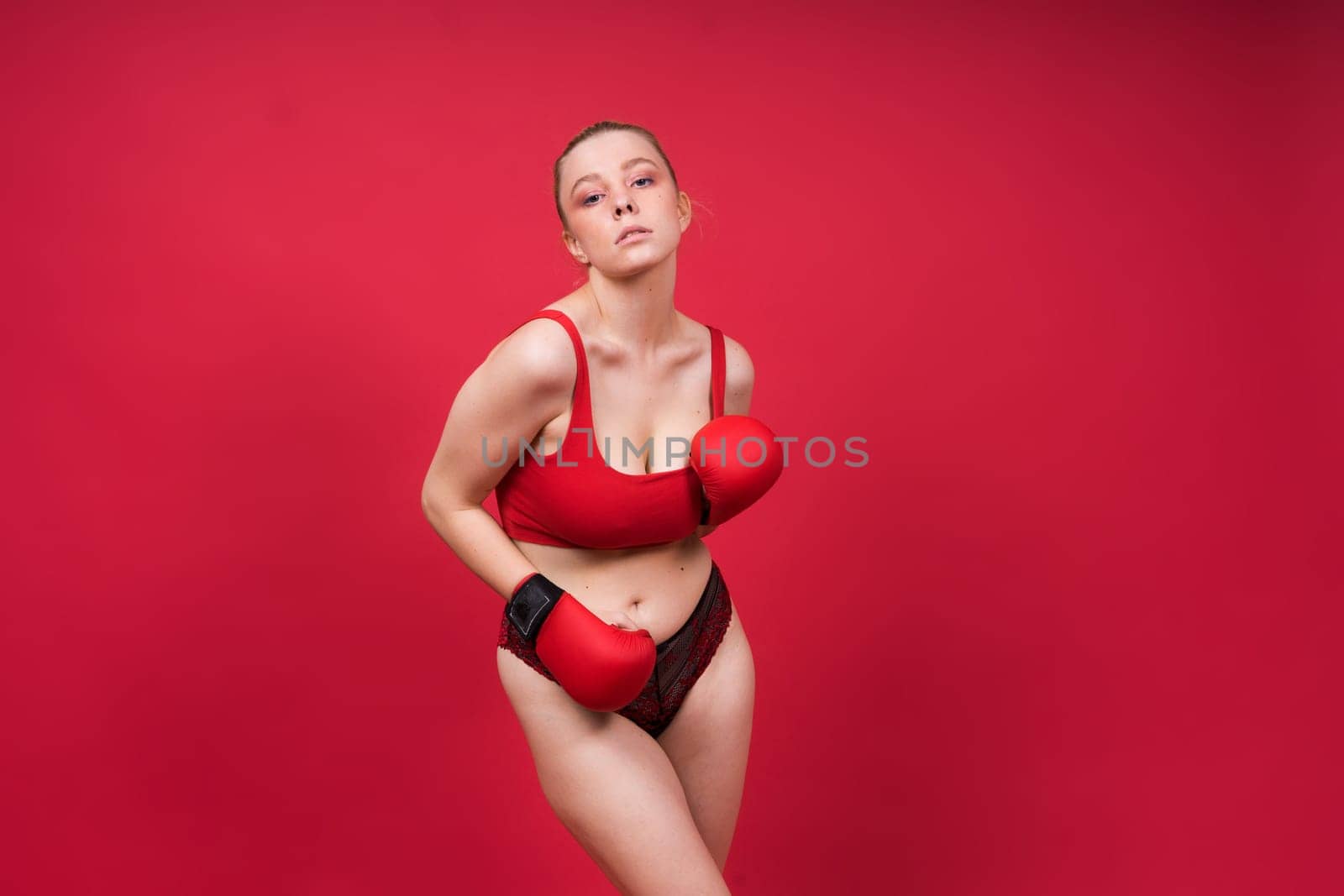 Image of seductive young woman boxer posing isolated on yellow red background in boxing gloves.