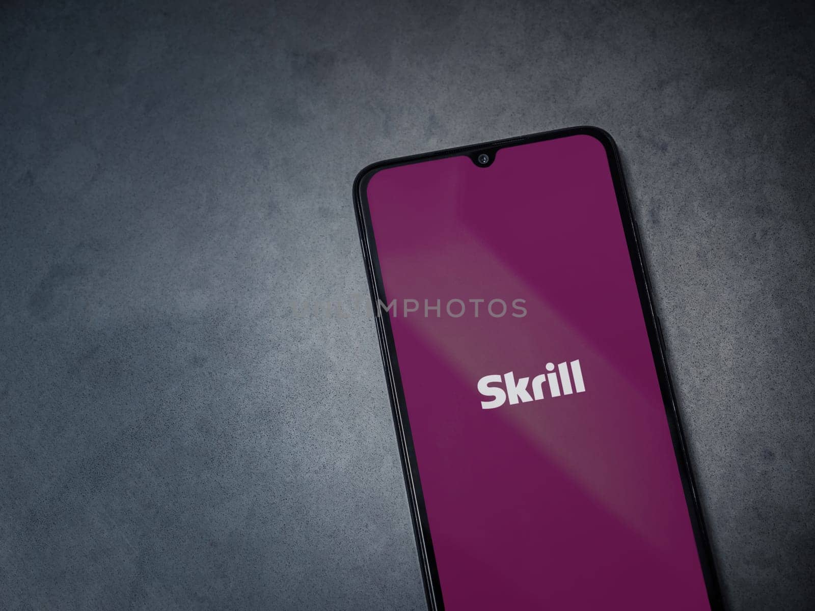 Lod, Israel - July 16,2023: Skrill app launch screen on smartphone on dark marble stone background. Top view flat lay with copy space.